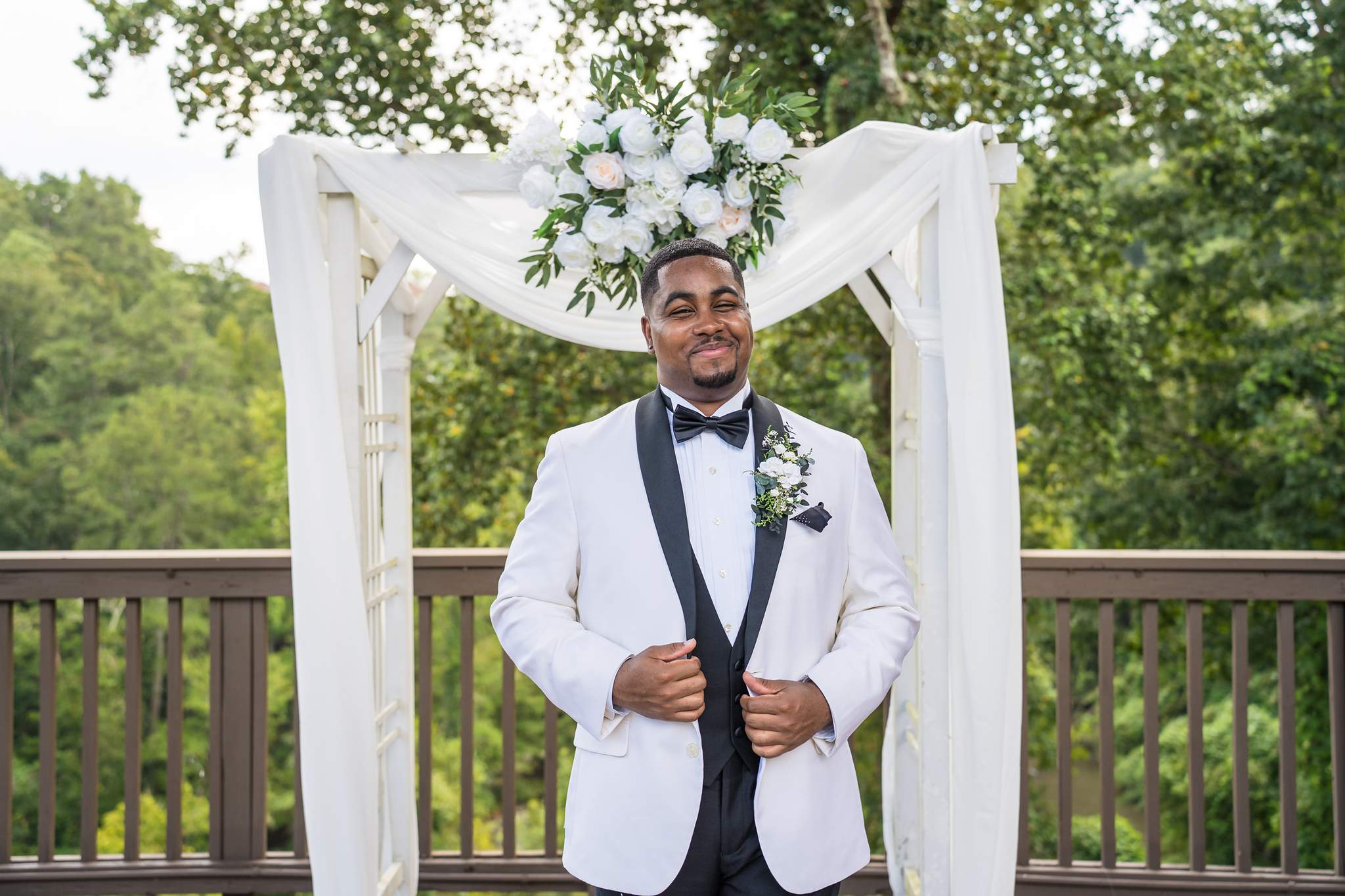 Groom portrait under the floral arbor on the Ivy Hall at Roswell Mill deck