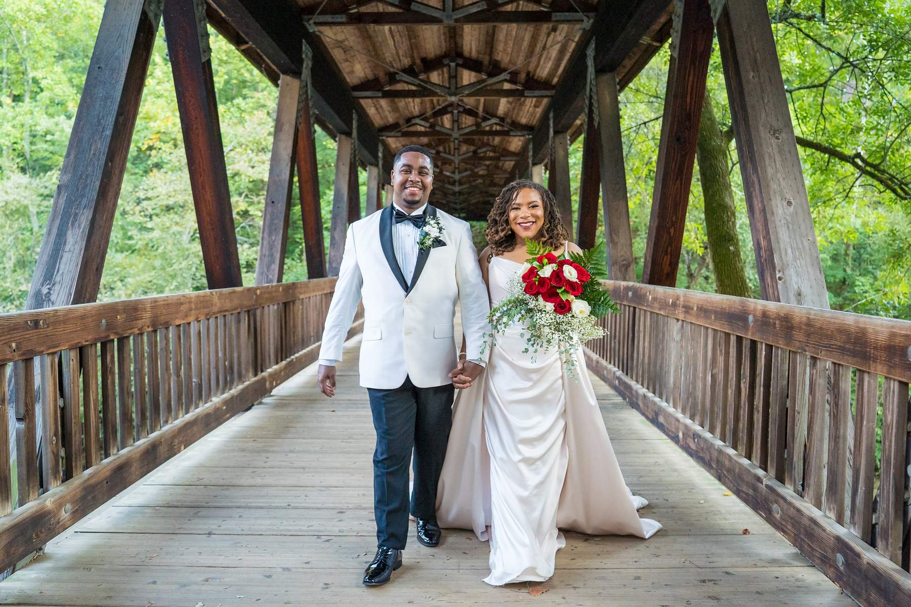 Couple walking across the covered bridge at Old Mill Park in Roswell