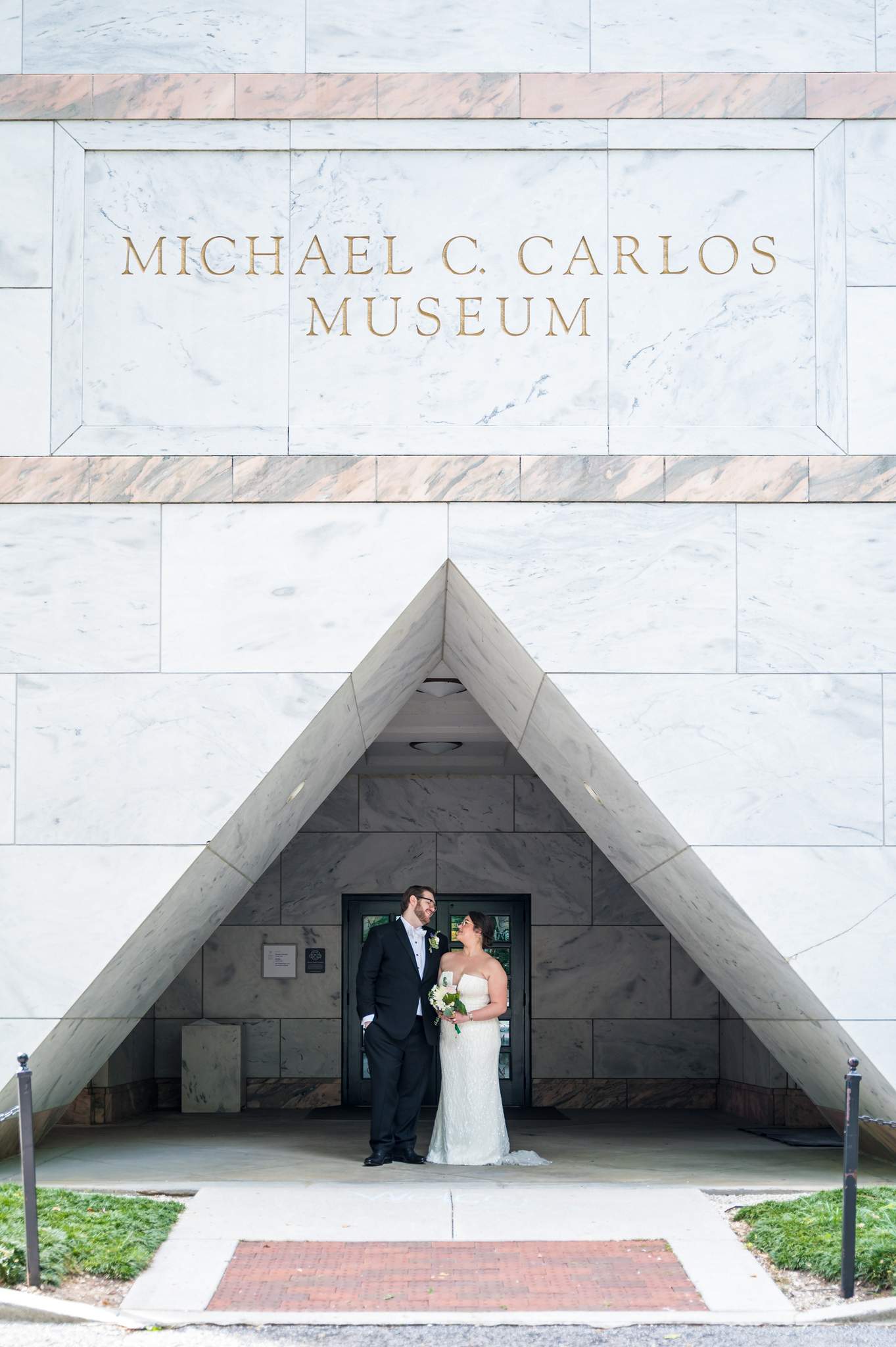Couple portrait in front of the marble facade of the Michael C. Carlos Museum