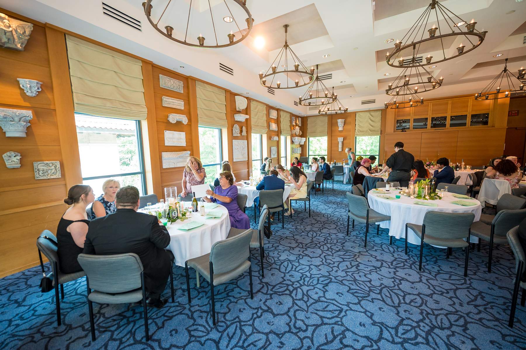 Guests at dinner under the chandeliers in Ackerman Hall