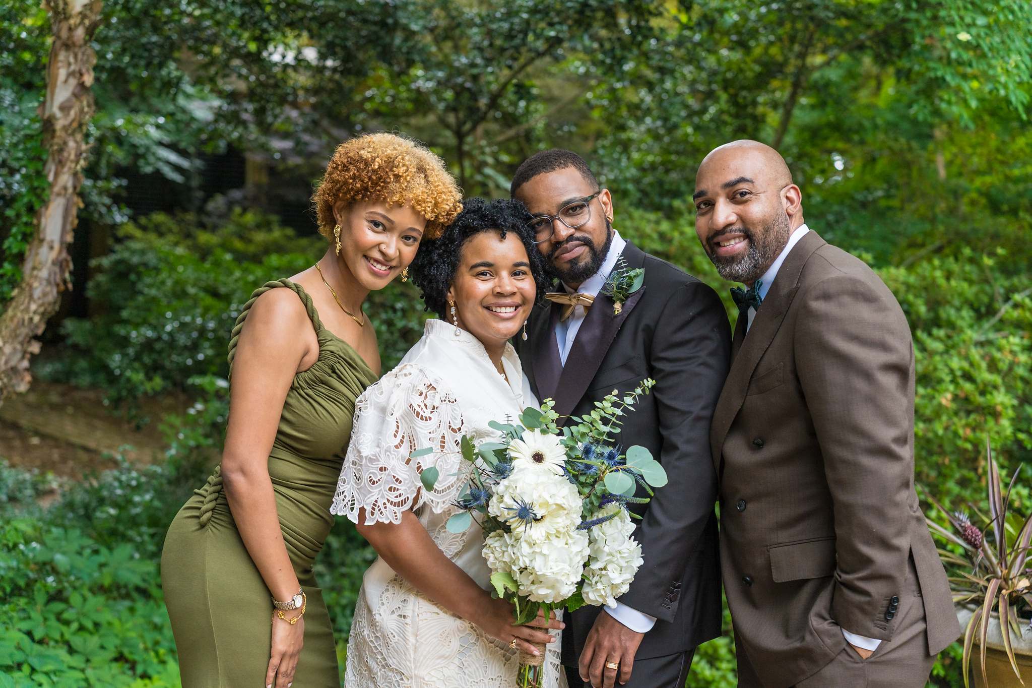Bride and groom with two guests in a garden after their small ceremony