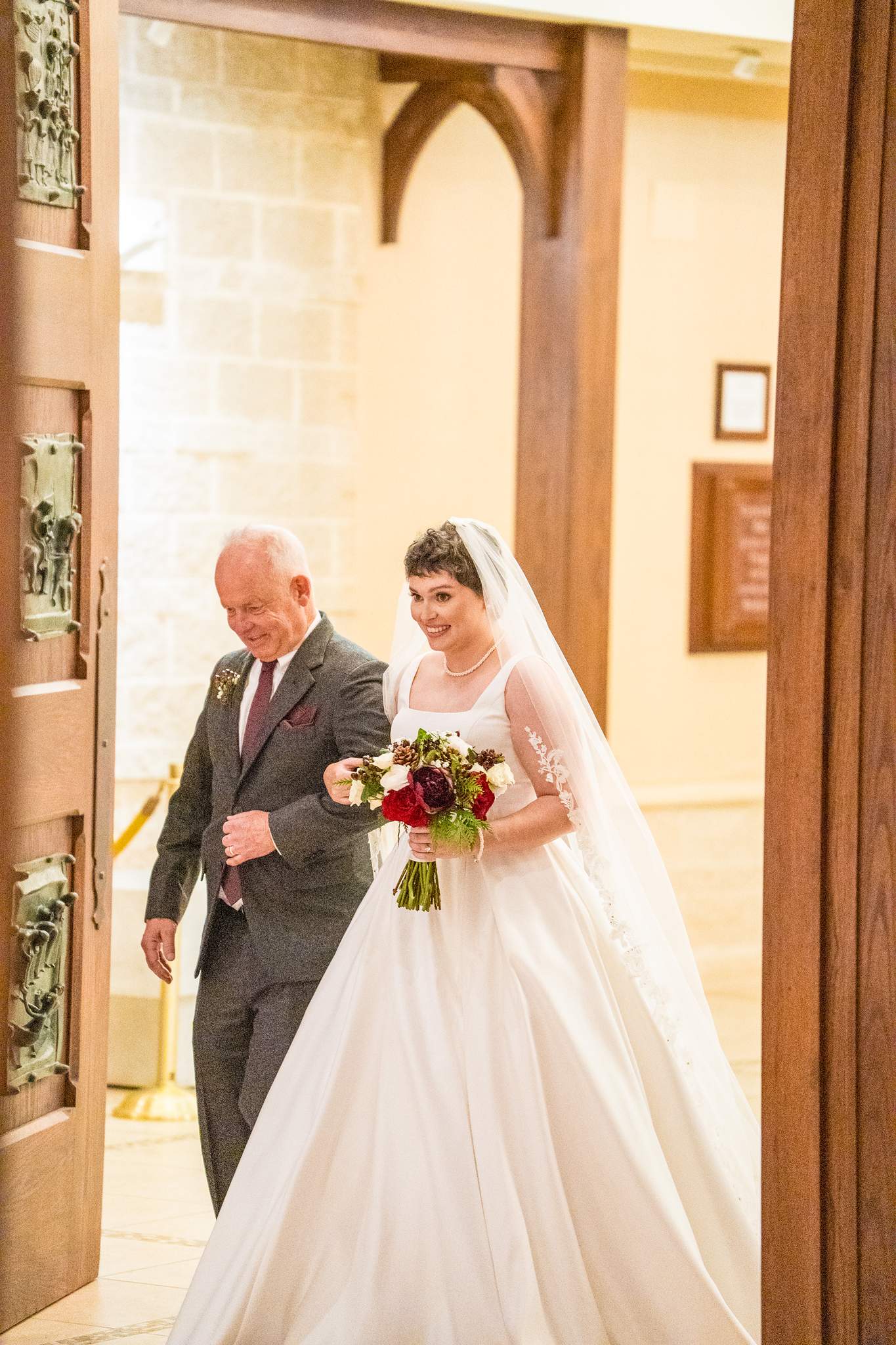 Bride being escorted to the church doors at Our Lady of the Assumption