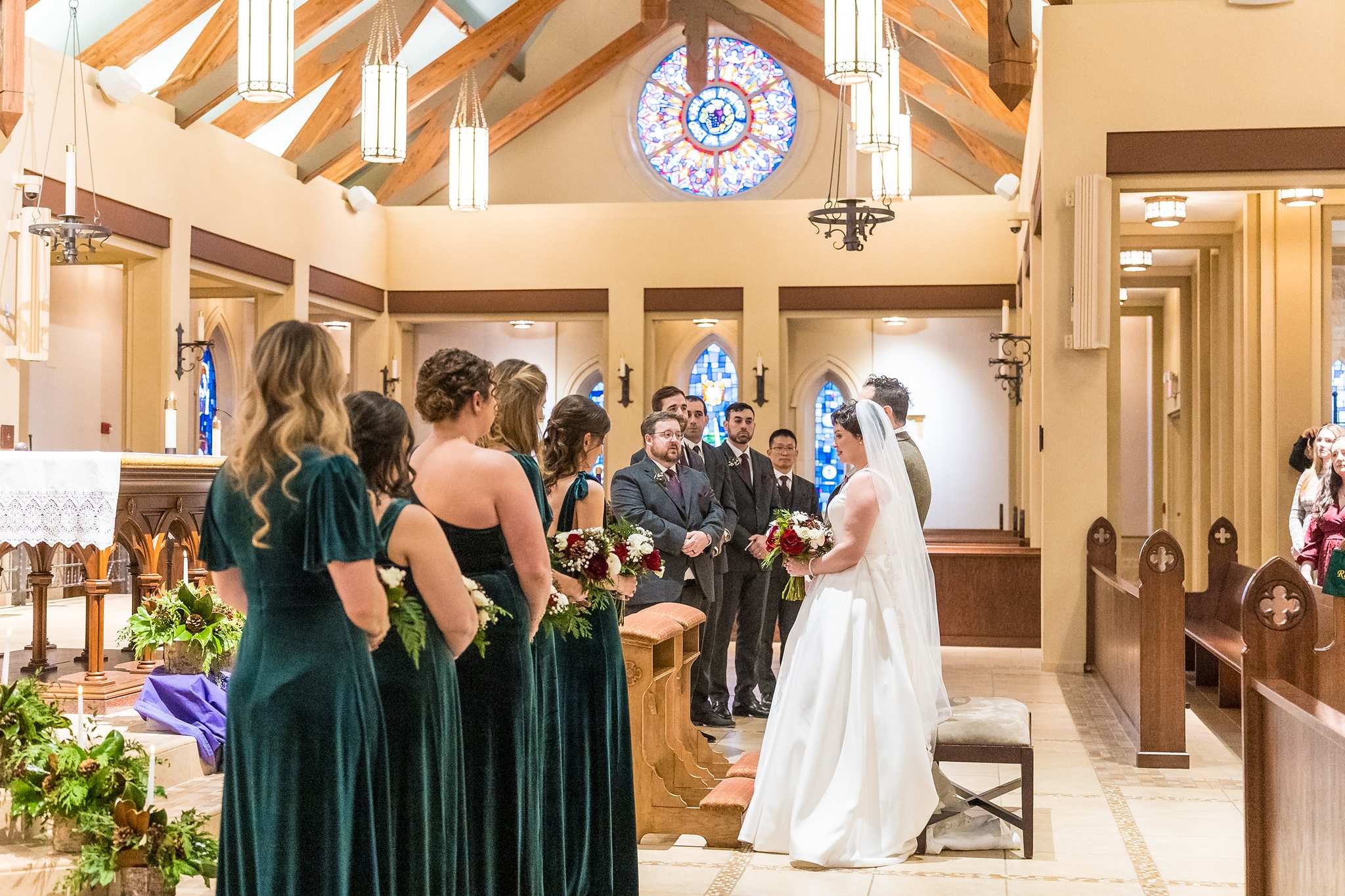 Bridesmaids in emerald velvet walking up the aisle at Our Lady of the Assumption