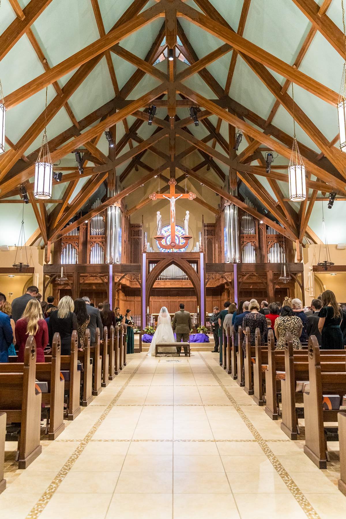 Wide view down the center aisle of Our Lady of the Assumption Catholic Church during a wedding