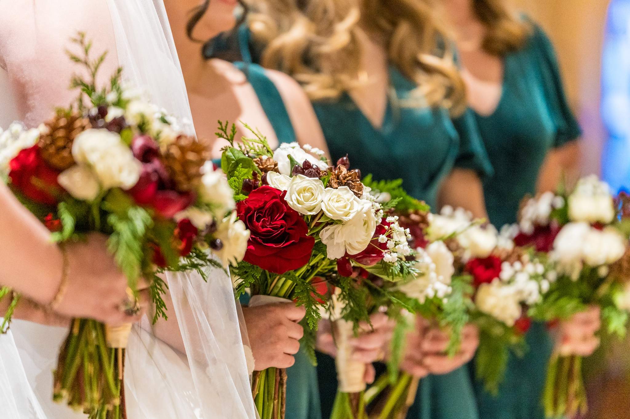 Bridesmaids holding red and white bouquets at a church wedding
