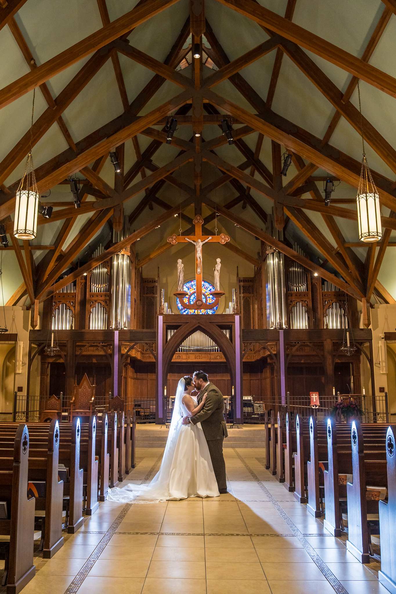 Wide portrait of the couple in the center aisle under the wood ceiling