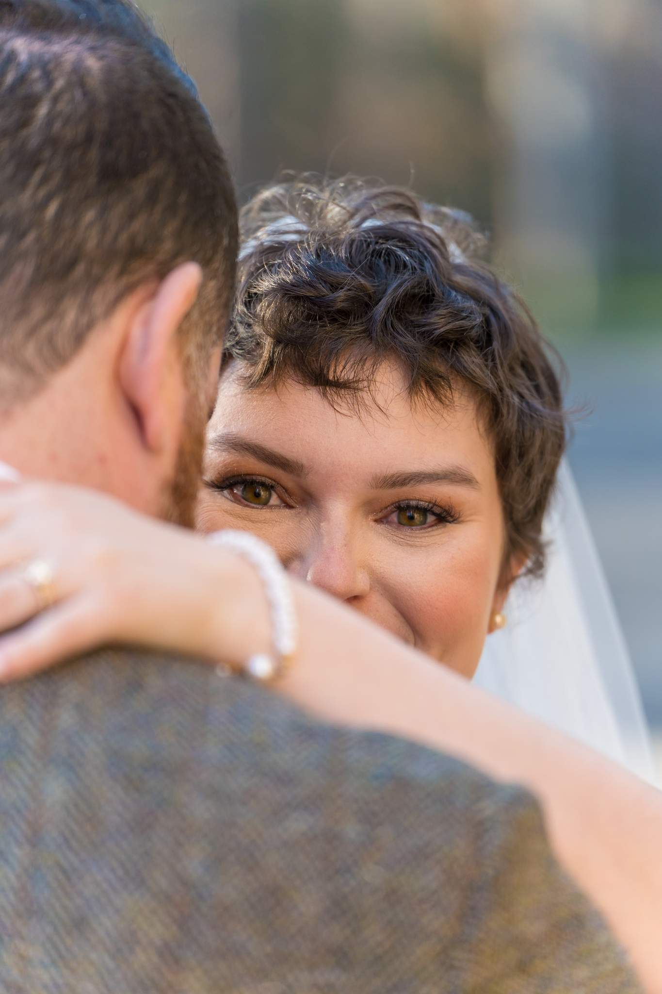 Bride smiling over the groom’s shoulder after their wedding