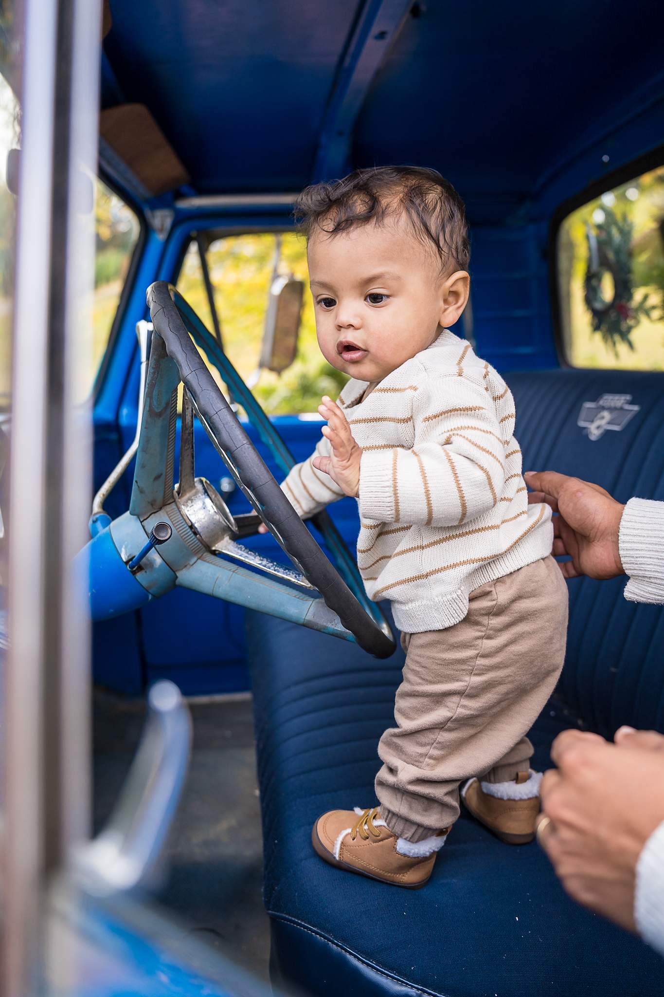 Baby standing at the steering wheel inside the 1965 Blue Christmas Truck