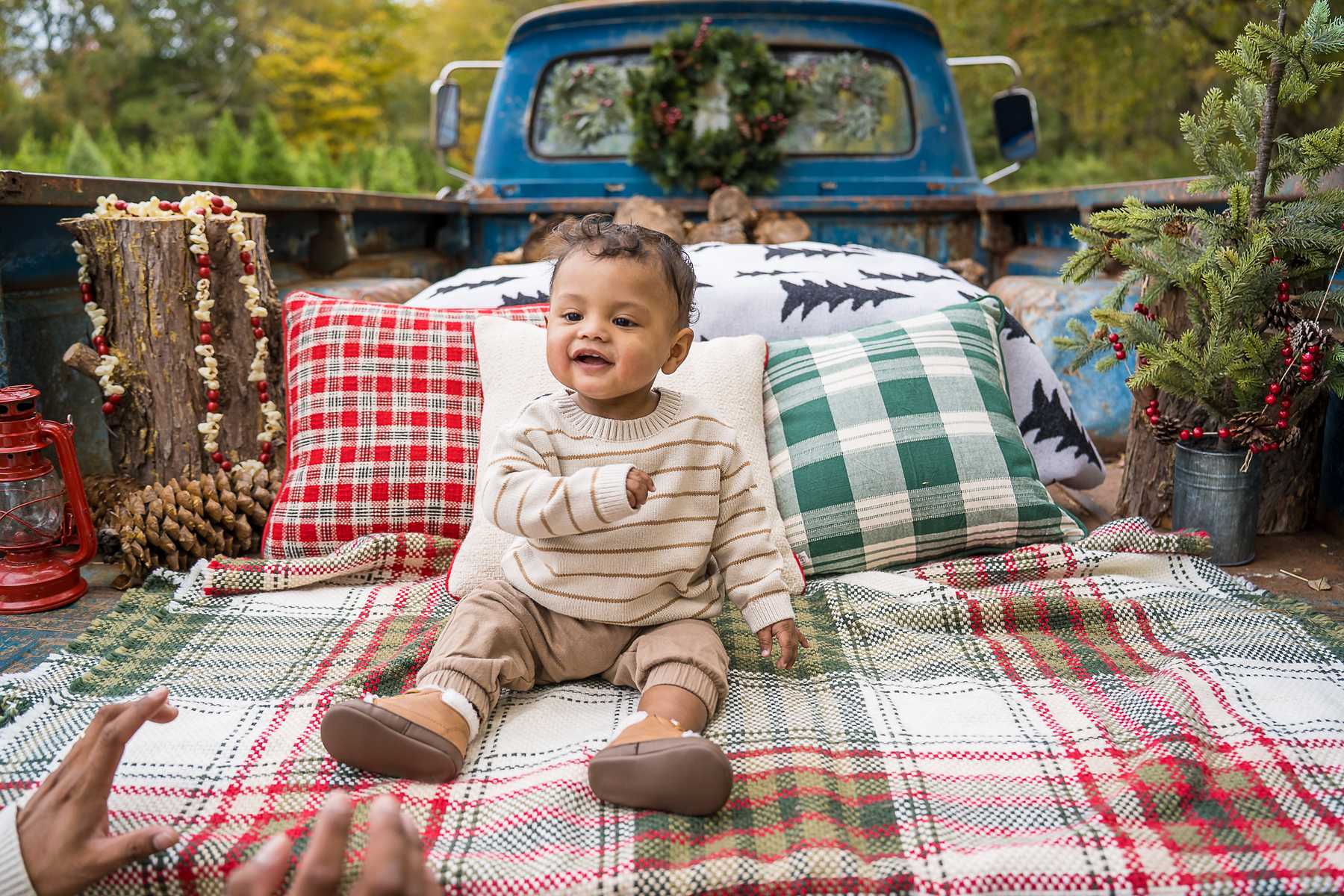 Smiling baby on plaid blankets and pillows in the back of the 1965 Blue Christmas Truck
