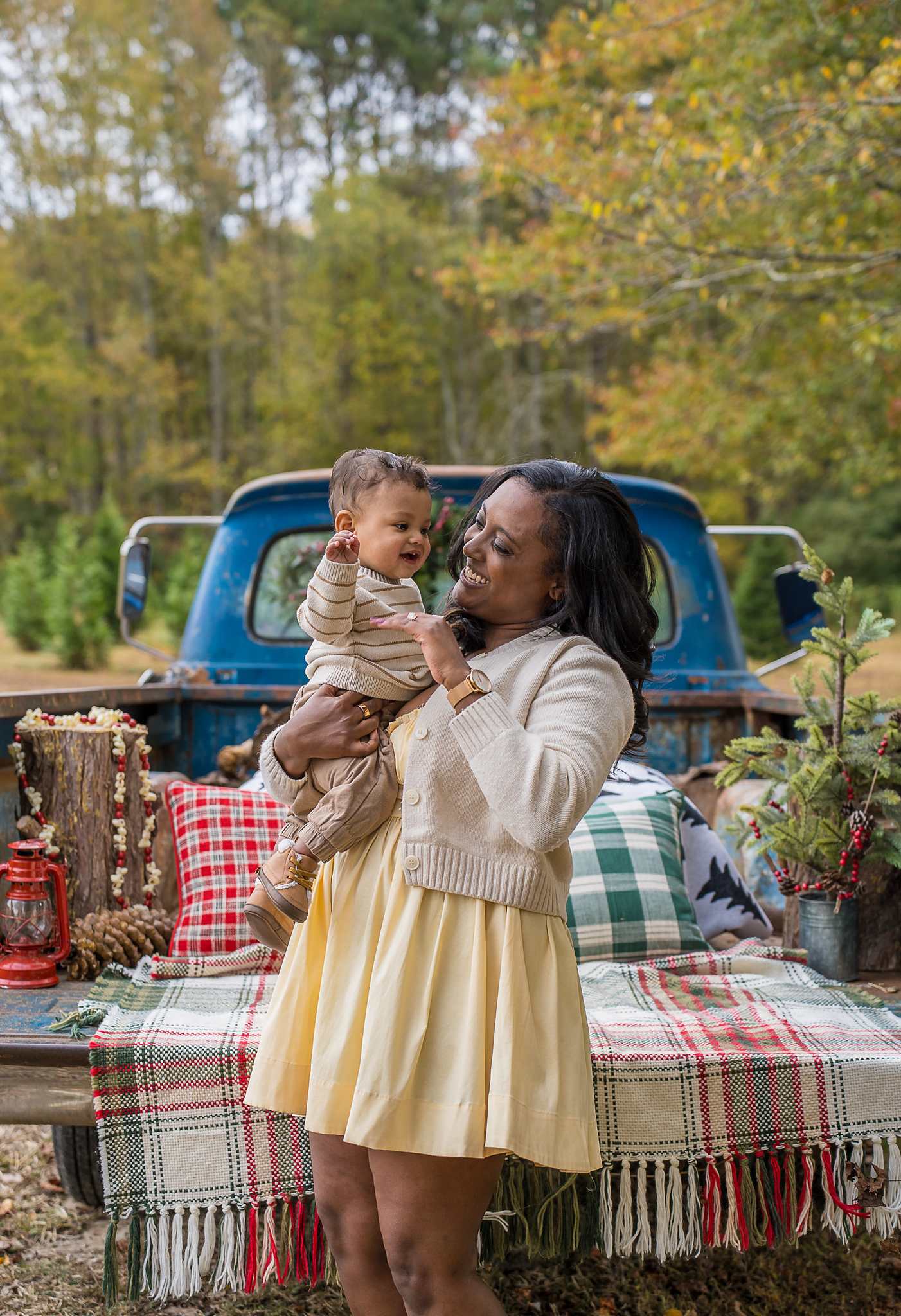 Mother holding her baby beside the 1965 Blue Christmas Truck at Prospect Farms