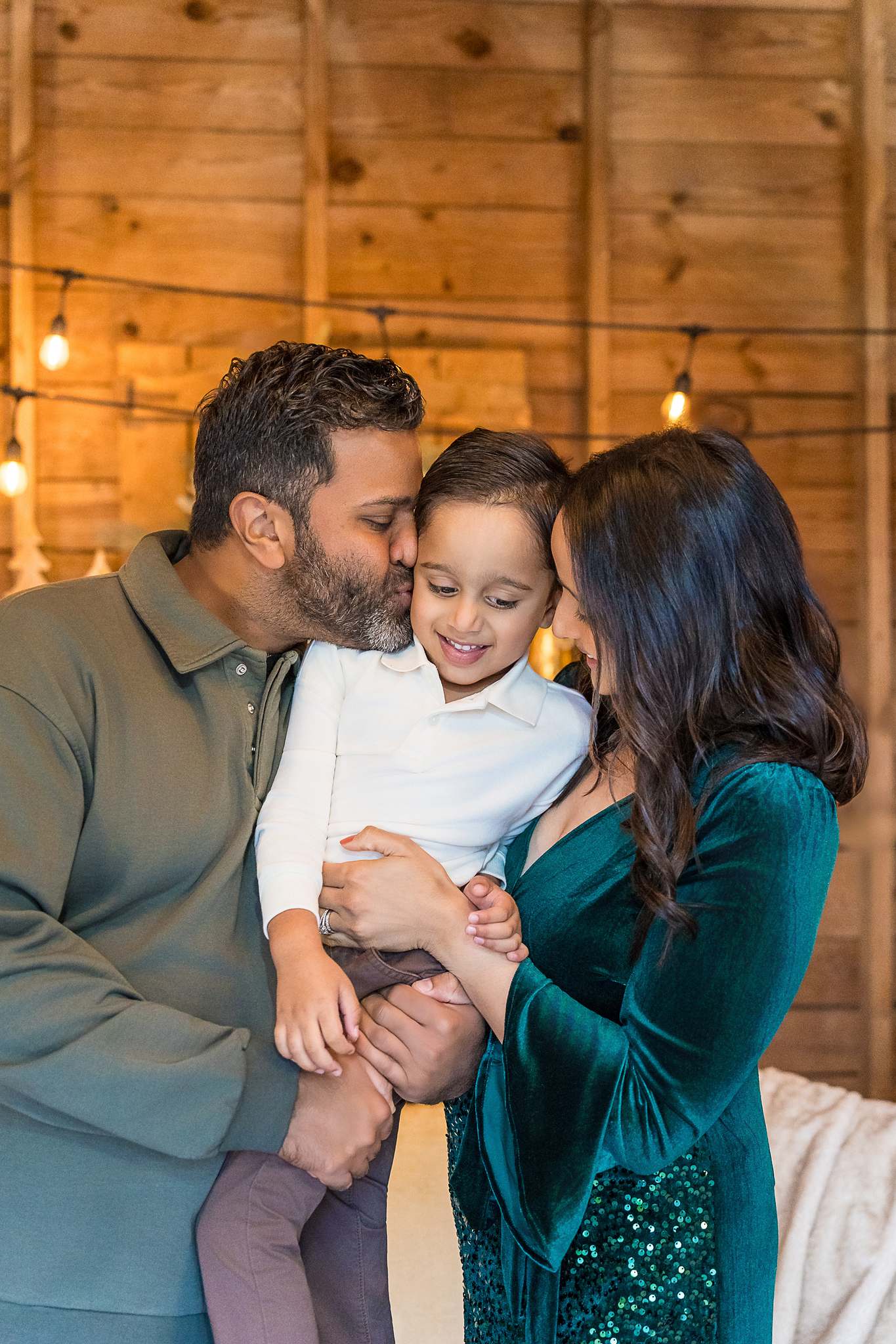 Parents kissing their son's cheeks in the Christmas Barn set at Prospect Farms