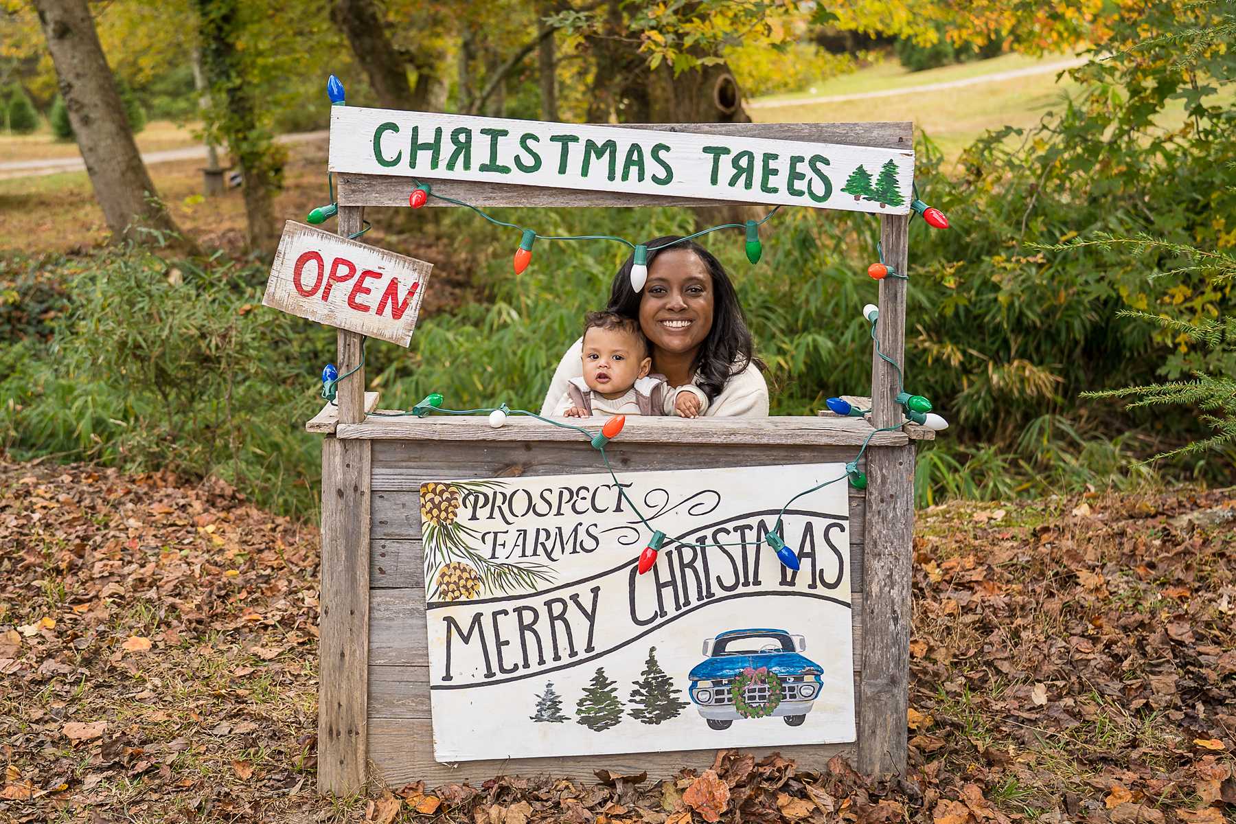 Mother and baby peeking over the Christmas tree stand sign at Prospect Farms