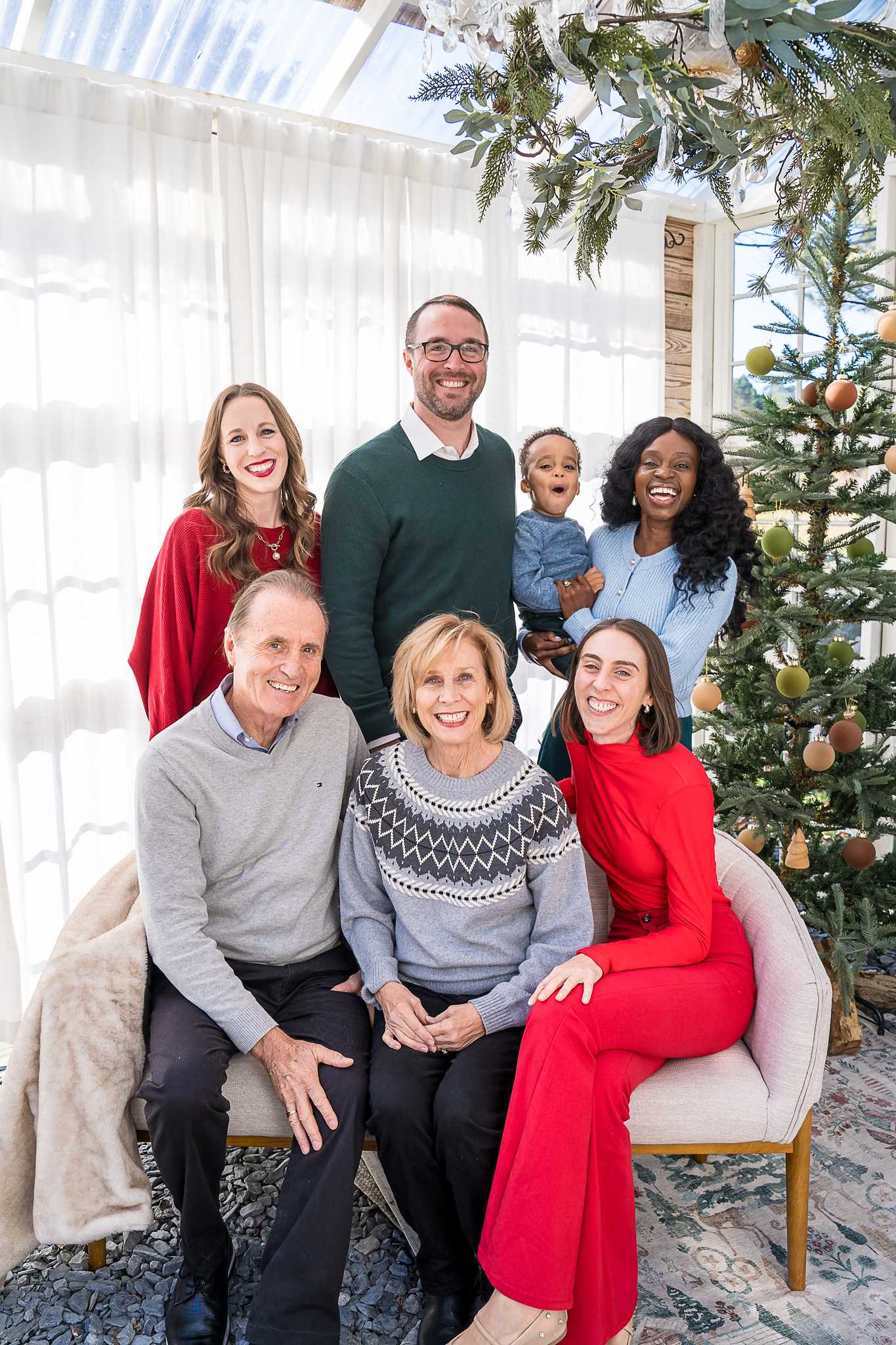 Extended family in red, green and neutral sweaters on the loveseat in the Greenhouse Christmas set at Prospect Farms