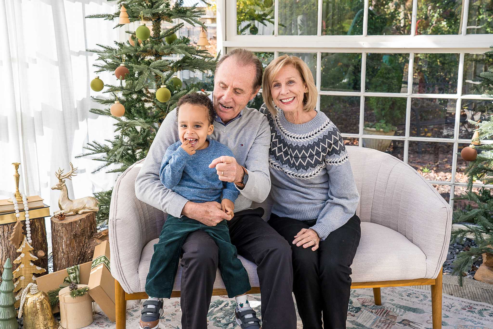 Grandparents with their grandson on the loveseat in the Greenhouse Christmas set at Prospect Farms
