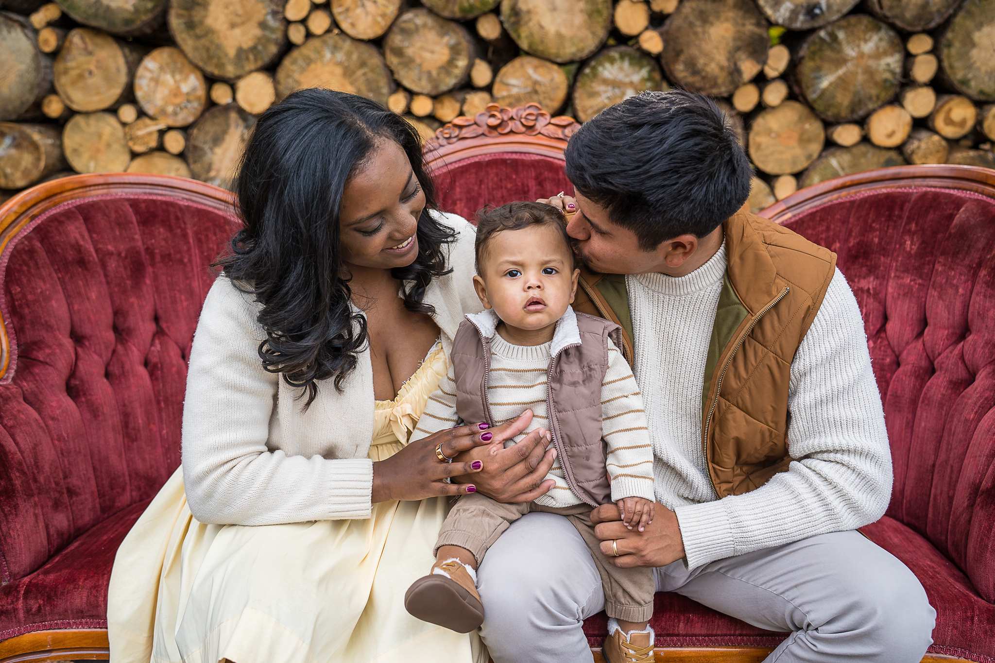 Family on the red velvet couch in front of the Log Wall at Prospect Farms