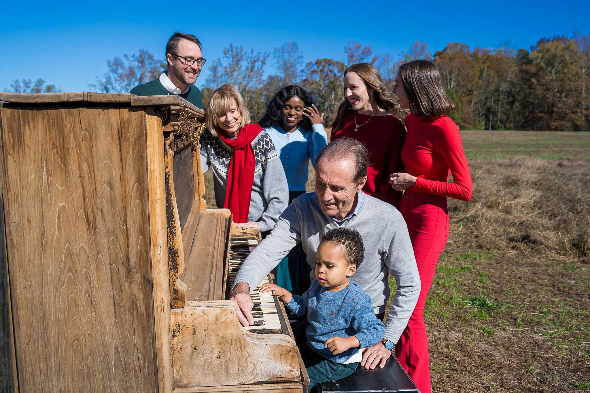 Grandfather and toddler playing the vintage piano while the family gathers in the field at Prospect Farms