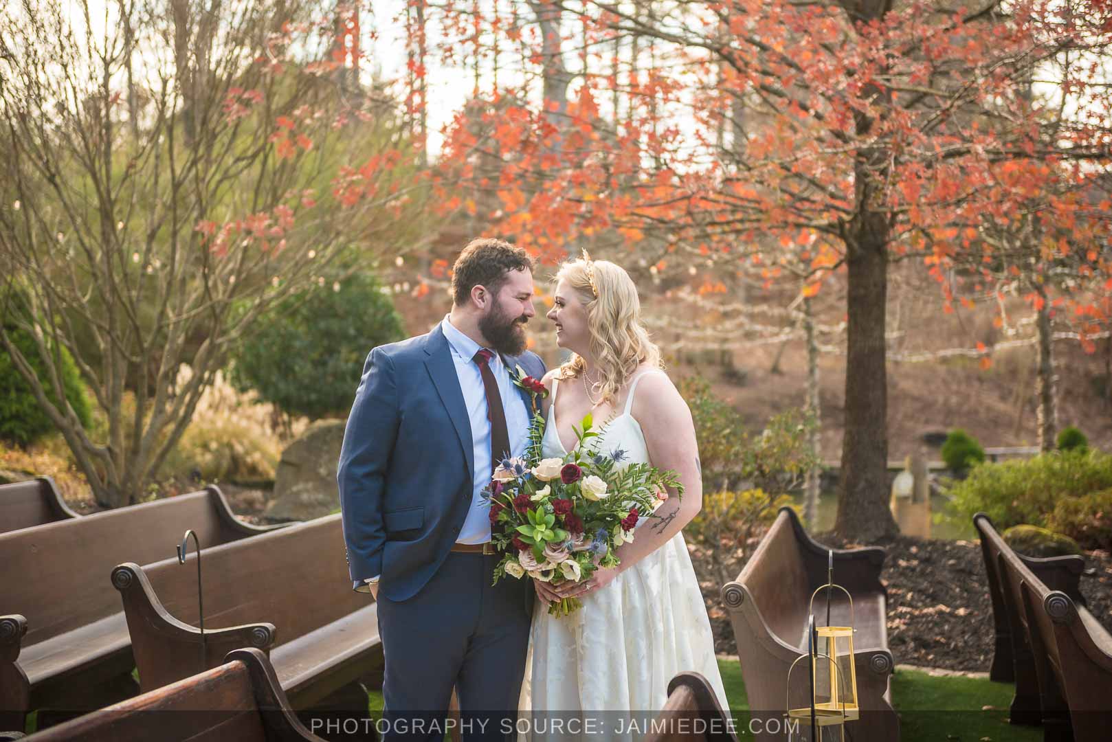 Bride and groom among ceremony benches under fall leaves at Rocky's Lake Estate, a fall wedding date couples book early in Georgia