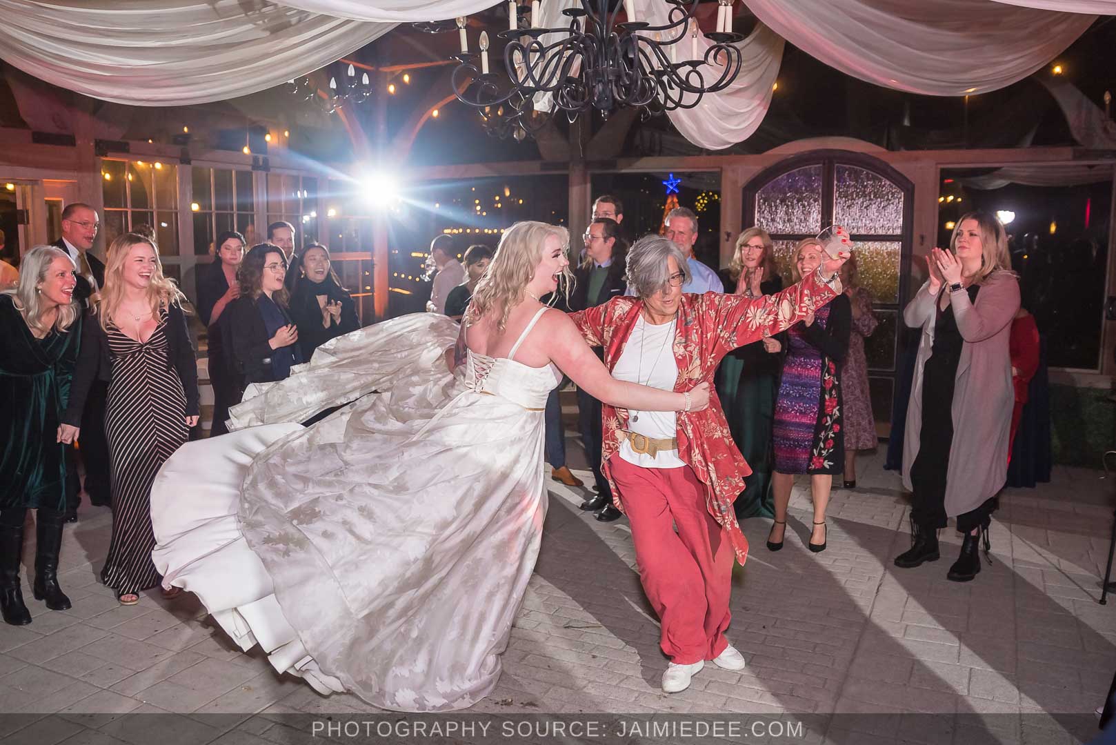 Rocky's Lake Estate Wedding Venue - reception - wedding guest dancing inside pavilion with ceiling drapes - bride twirling in her dress with guest