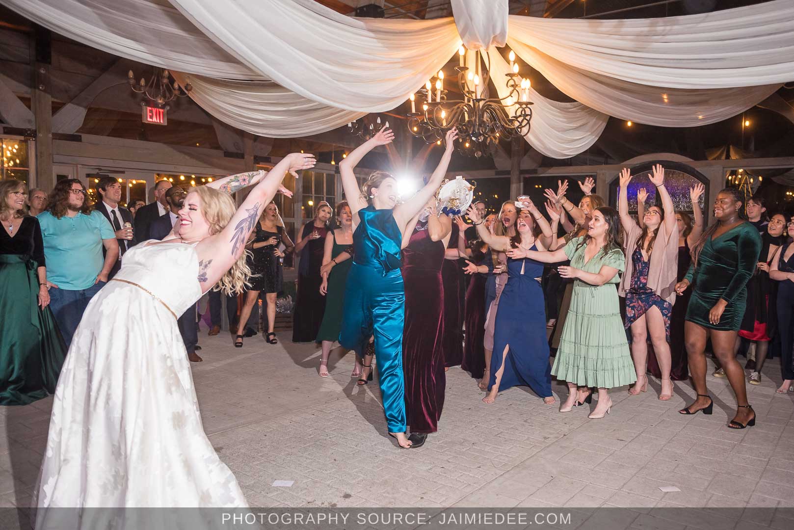 Rocky's Lake Estate Wedding Venue - reception - bride tosses bouquet inside pavilion with ceiling drapes - bouquet toss