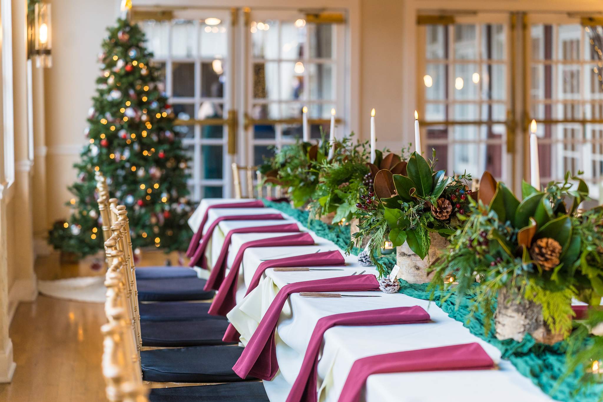 Head table with a Christmas tree and greenery garland at Roswell Mill Club