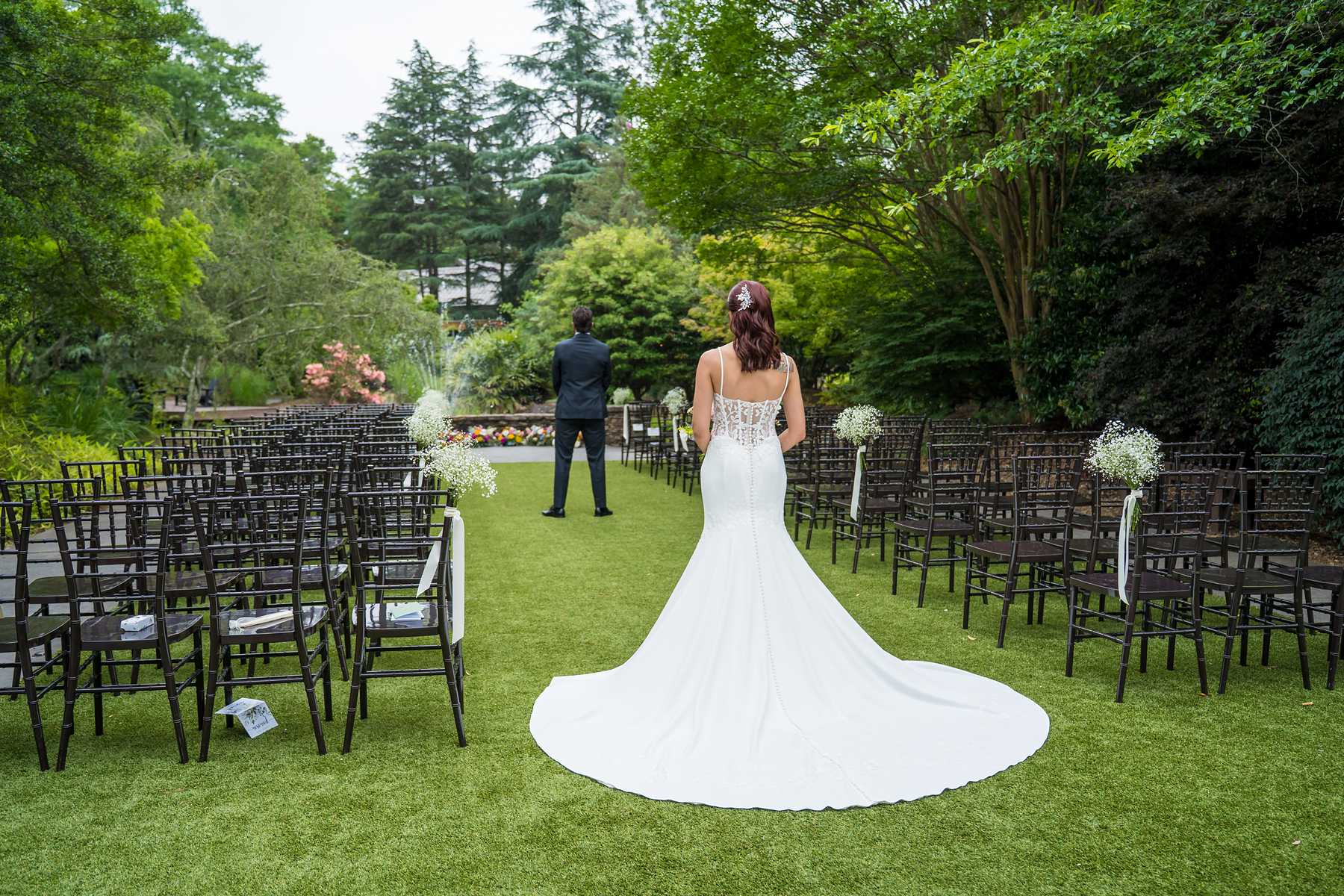 Bride walking toward the groom on the ceremony lawn for a first look at Shiloh Gardens