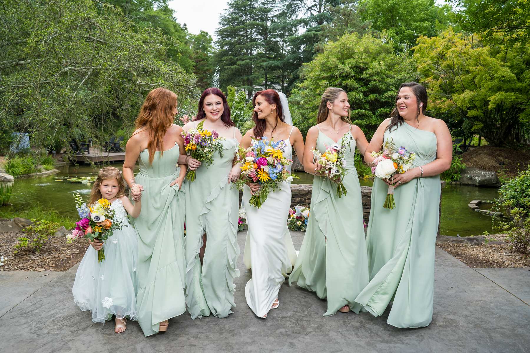 Bride with her bridesmaids in sage green dresses in the gardens at Shiloh Gardens
