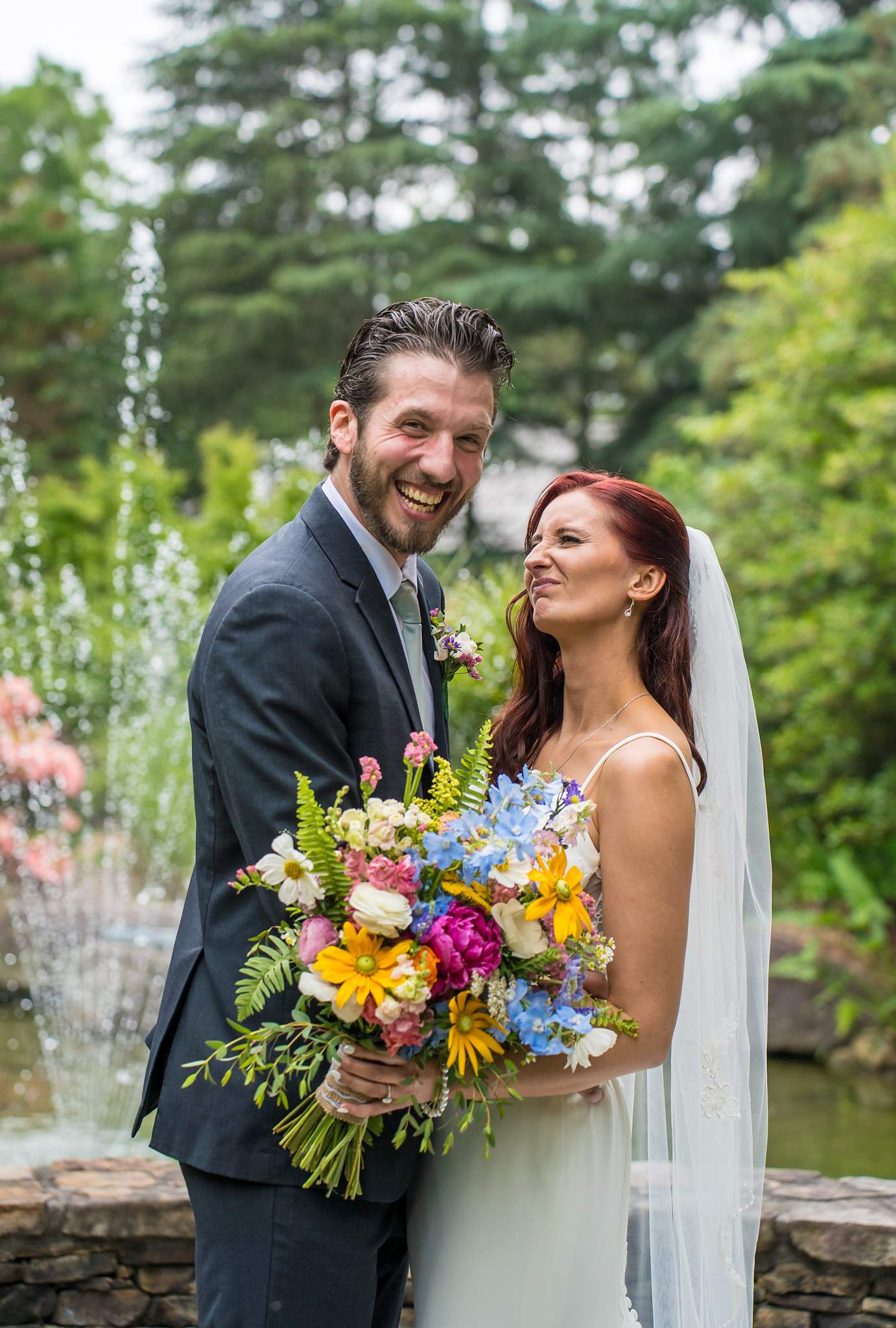 Couple laughing together with a colorful bouquet by the fountain at Shiloh Gardens