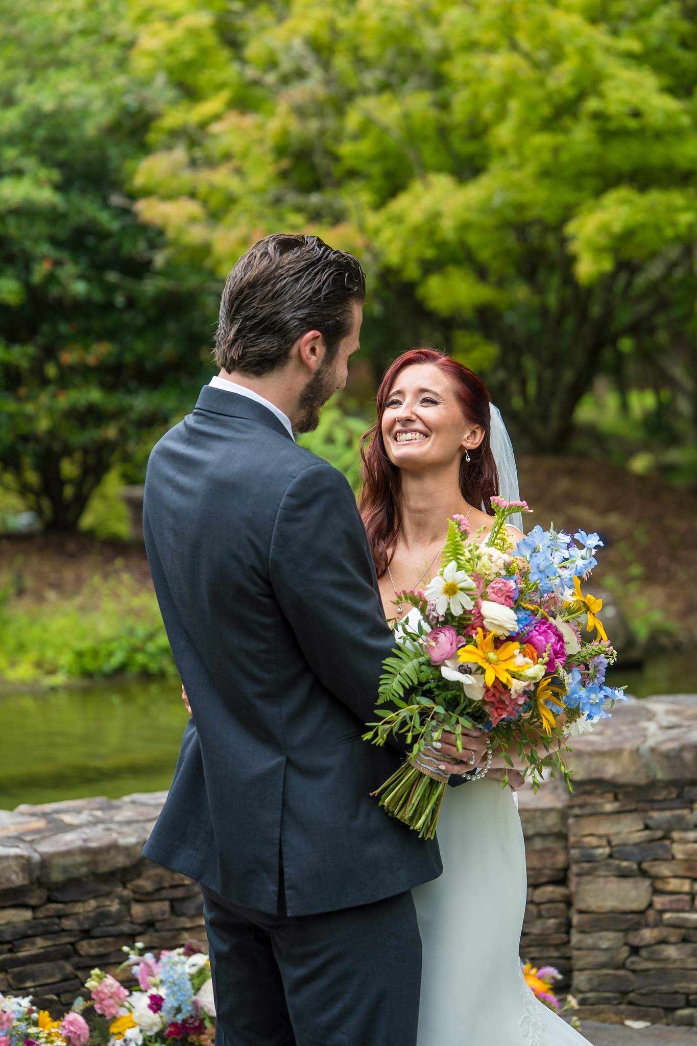 Bride and groom portrait beside the stone pond wall at Shiloh Gardens