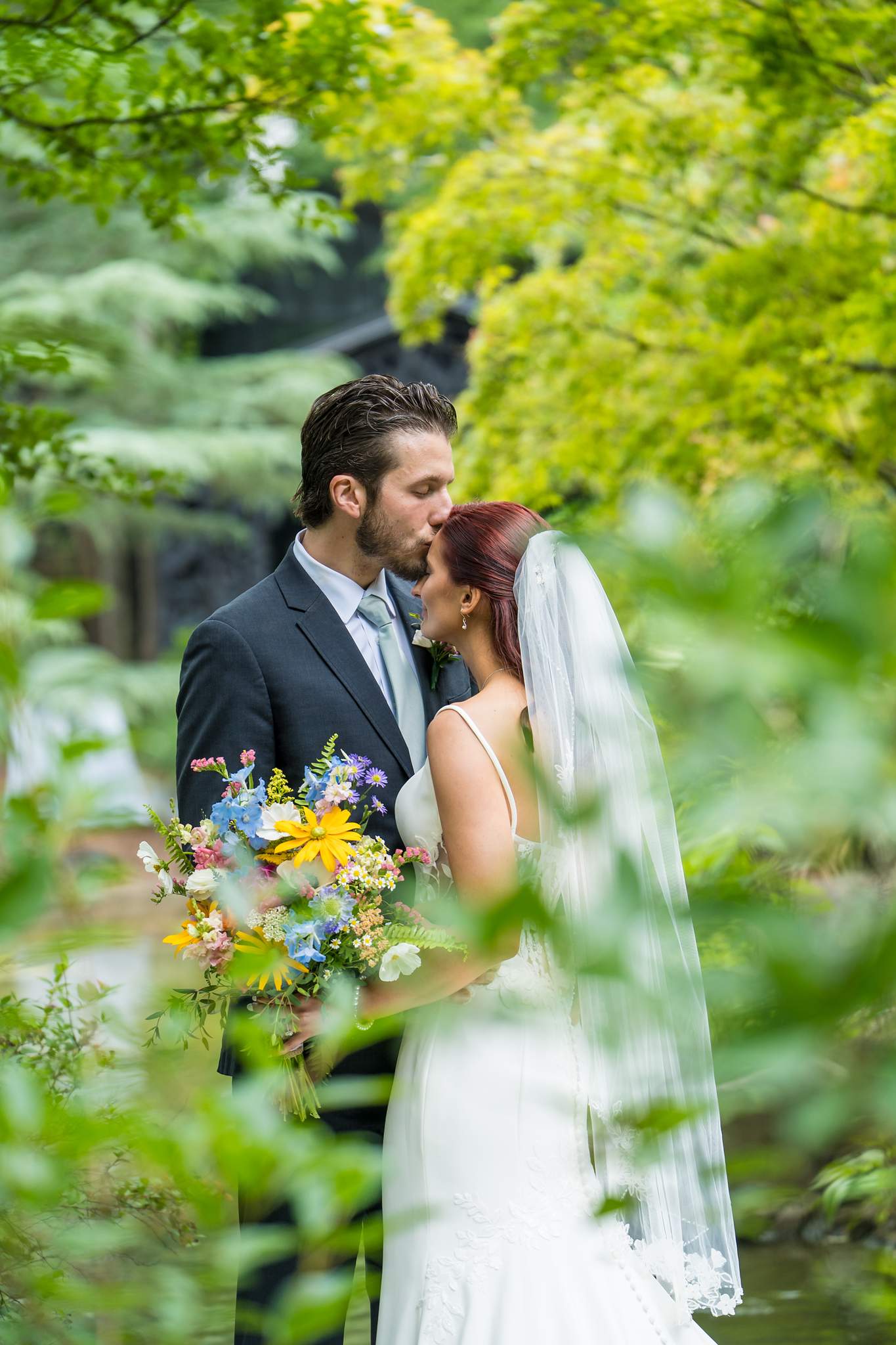 Couple portrait framed by green Japanese maples at Shiloh Gardens
