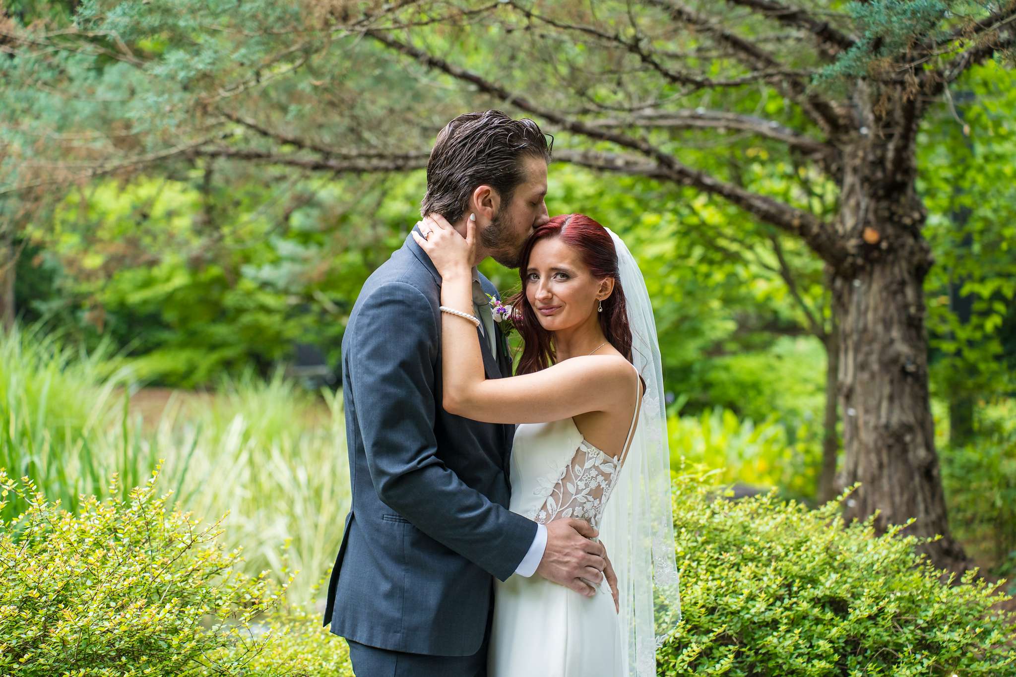 Groom kissing the bride on the forehead in the gardens at Shiloh Gardens