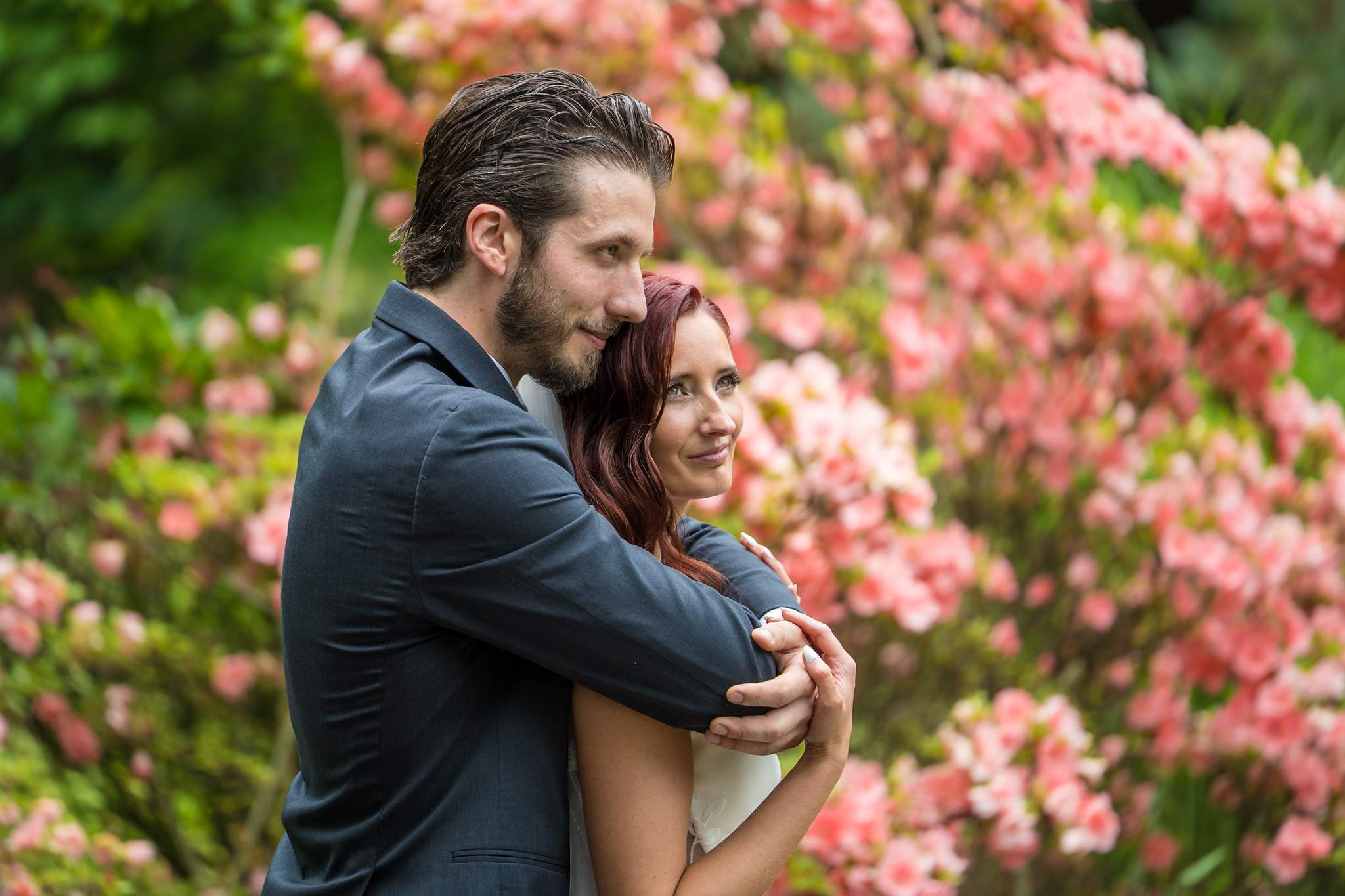 Couple embracing in front of blooming pink azaleas at Shiloh Gardens