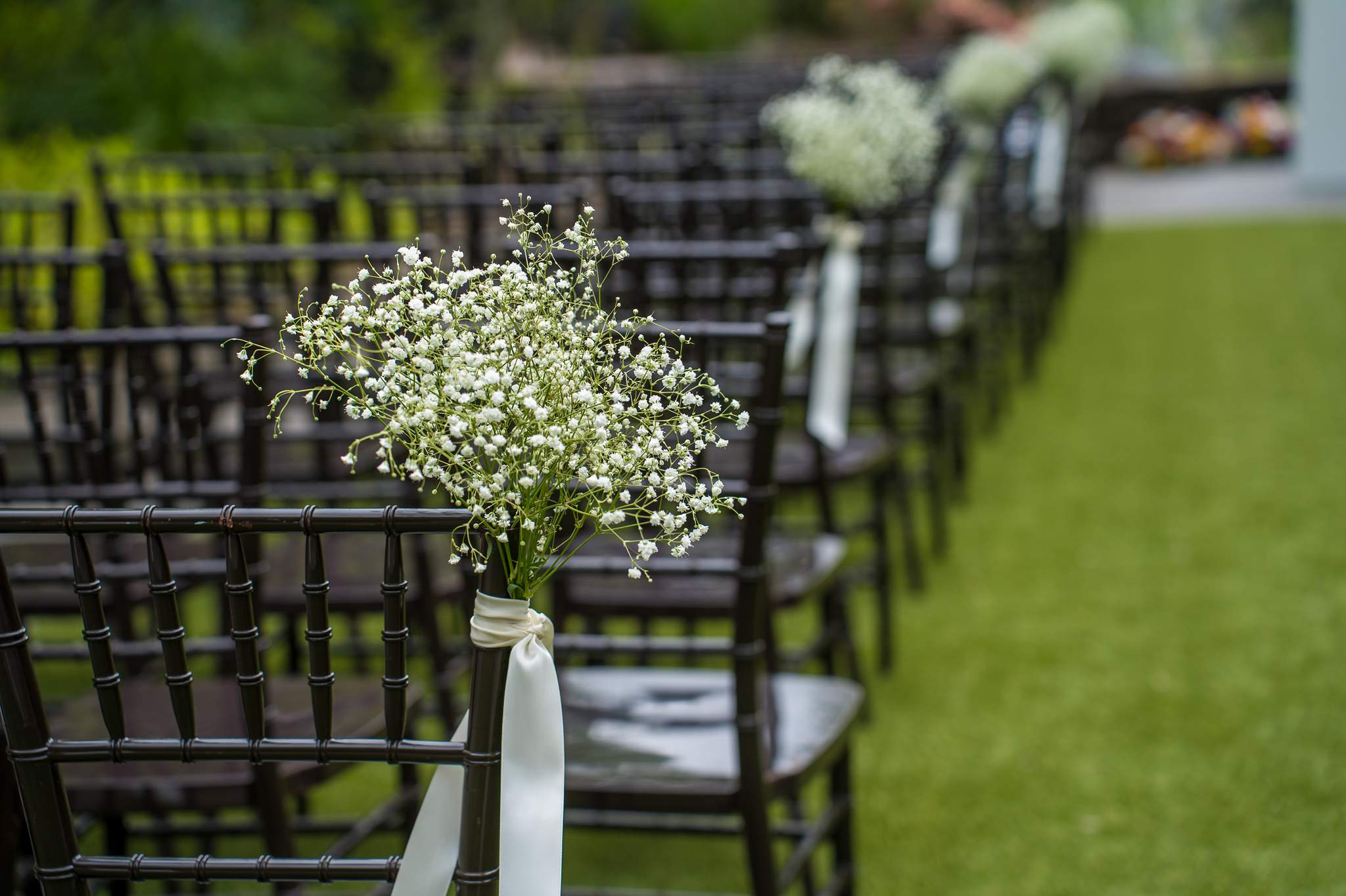 Aisle chairs with baby’s breath arrangements on the Shiloh Gardens ceremony lawn