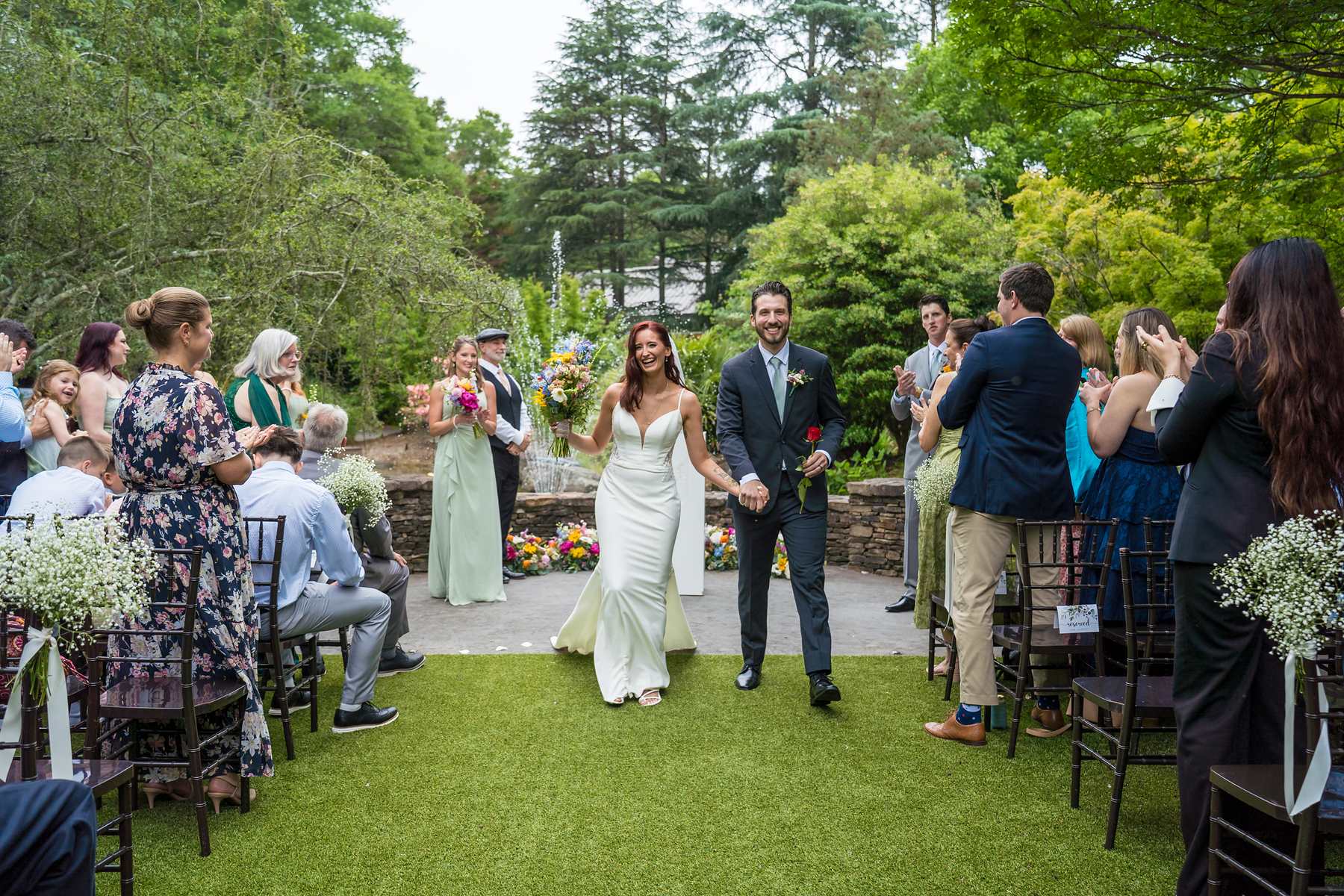 Couple walking back up the aisle as guests celebrate at Shiloh Gardens