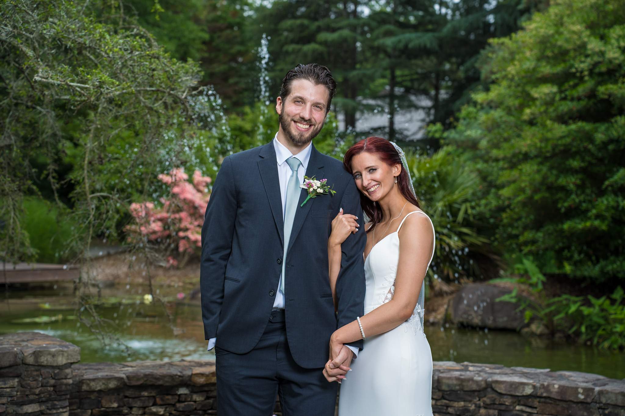 Couple smiling beside the pond and pink azaleas at Shiloh Gardens