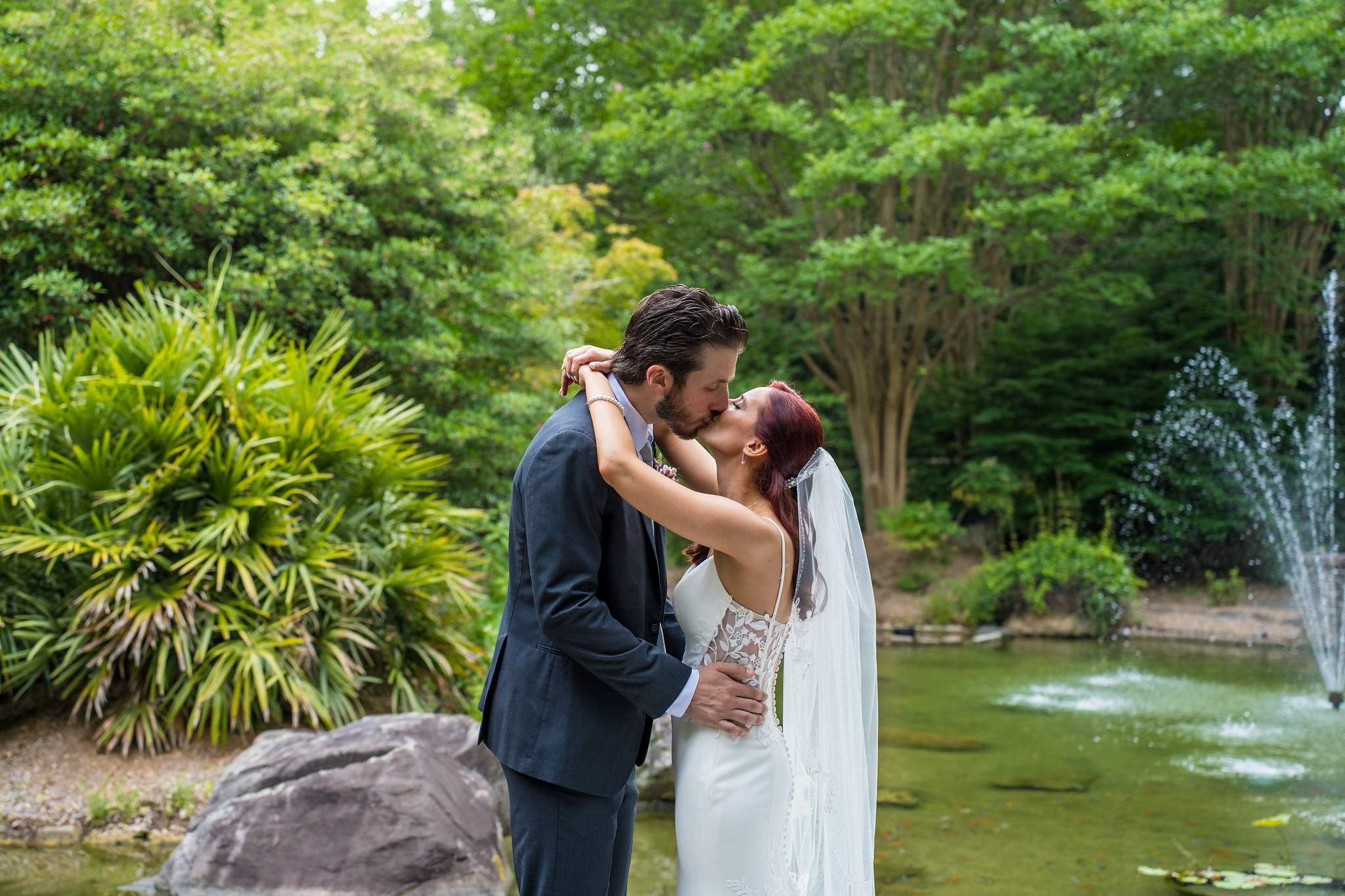 Groom kissing the bride by the lake fountain at Shiloh Gardens