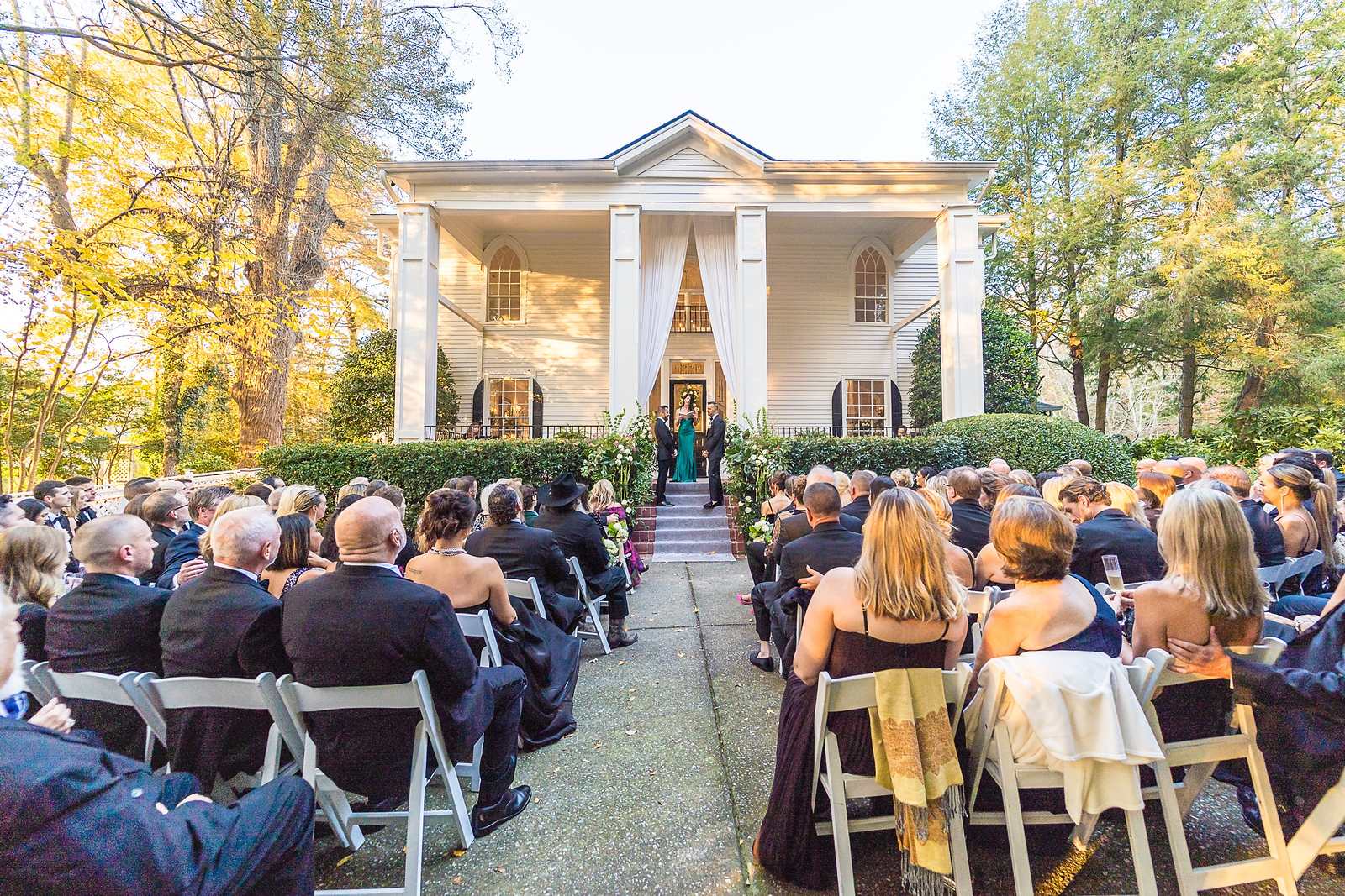 Guests seated for an outdoor ceremony facing the historic home at The Cedars in Acworth