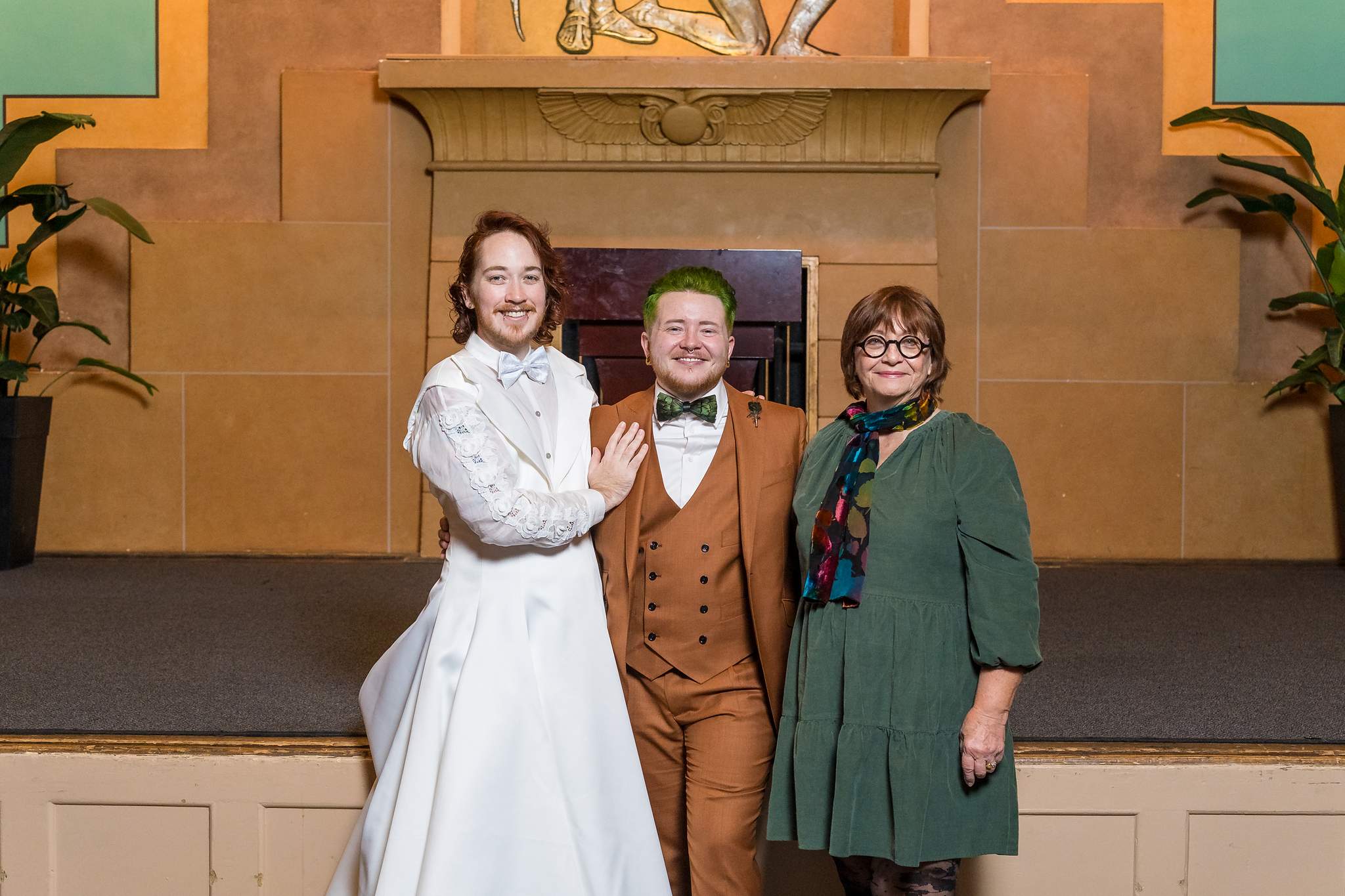 Couple with family in front of the Egyptian Ballroom stage wall