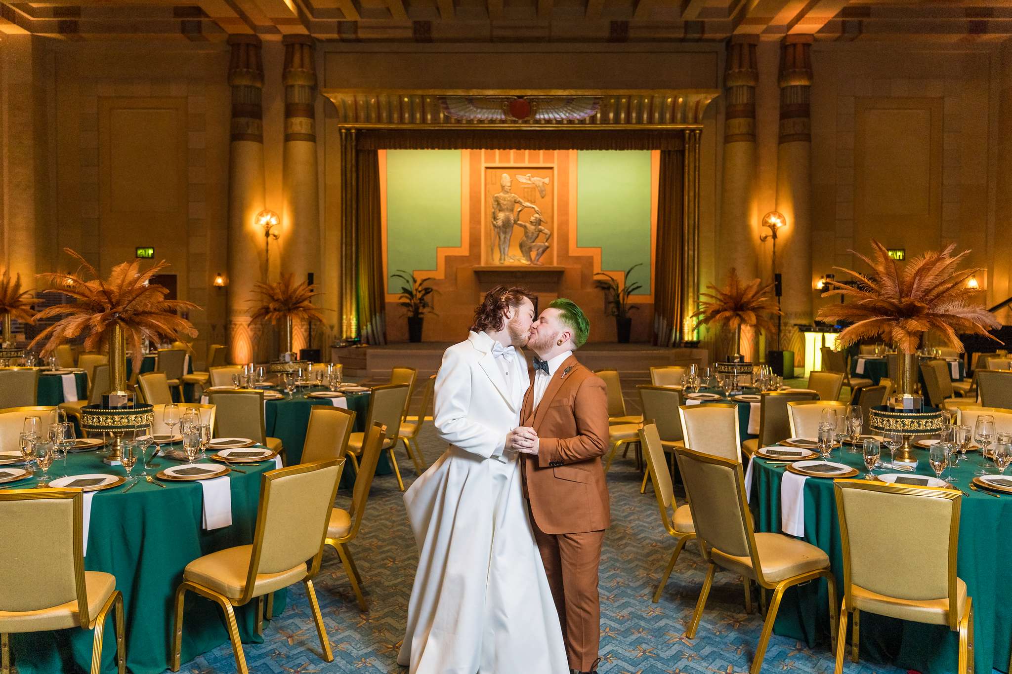Couple kissing among the reception tables in the Egyptian Ballroom