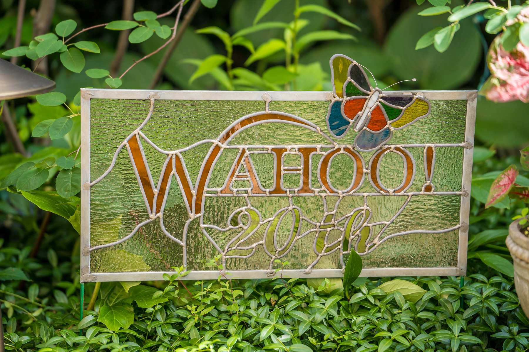 Stained glass Wahoo! Grill sign surrounded by greenery