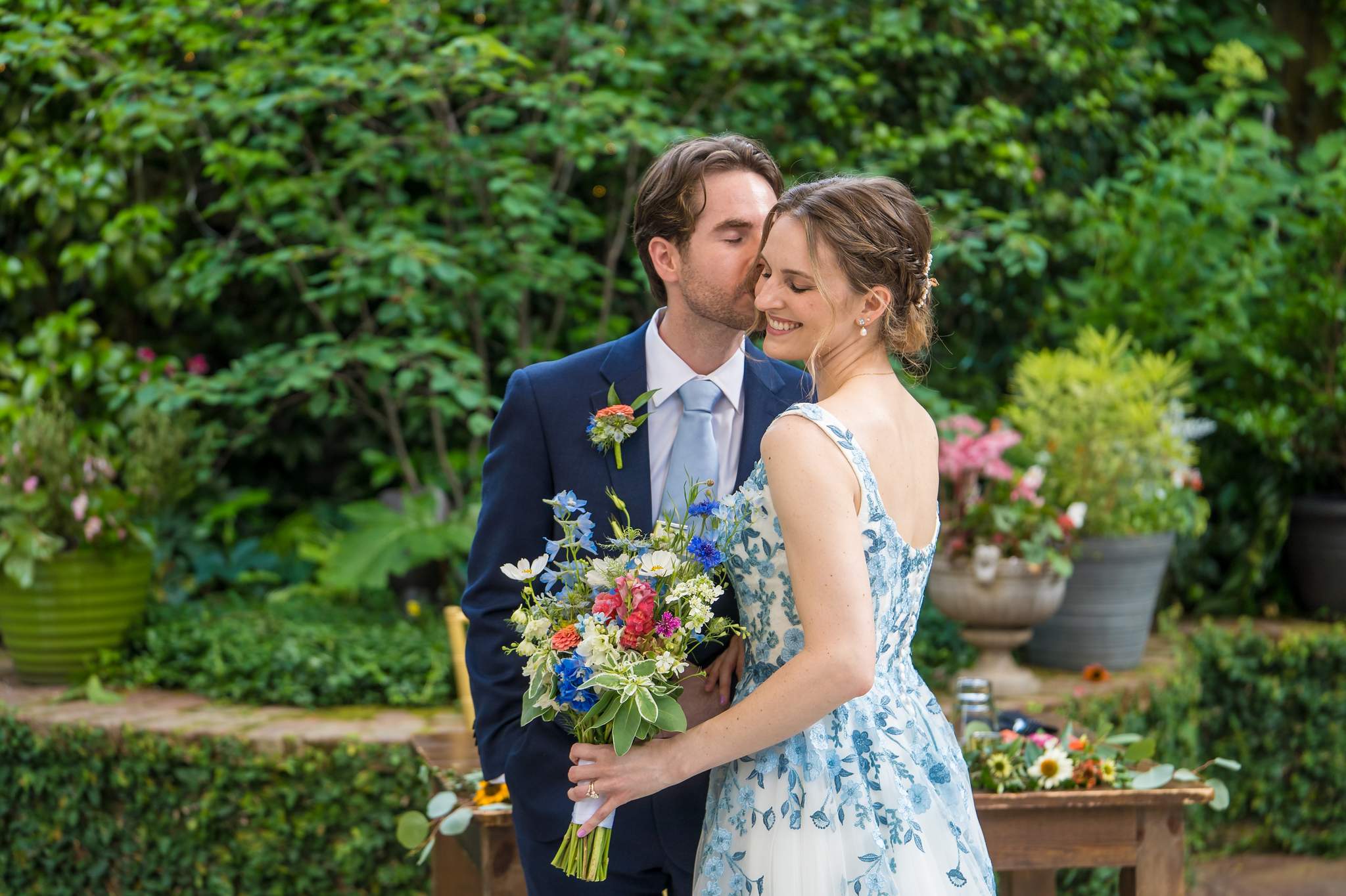 Groom kissing the bride on the cheek in the Wahoo! Grill garden