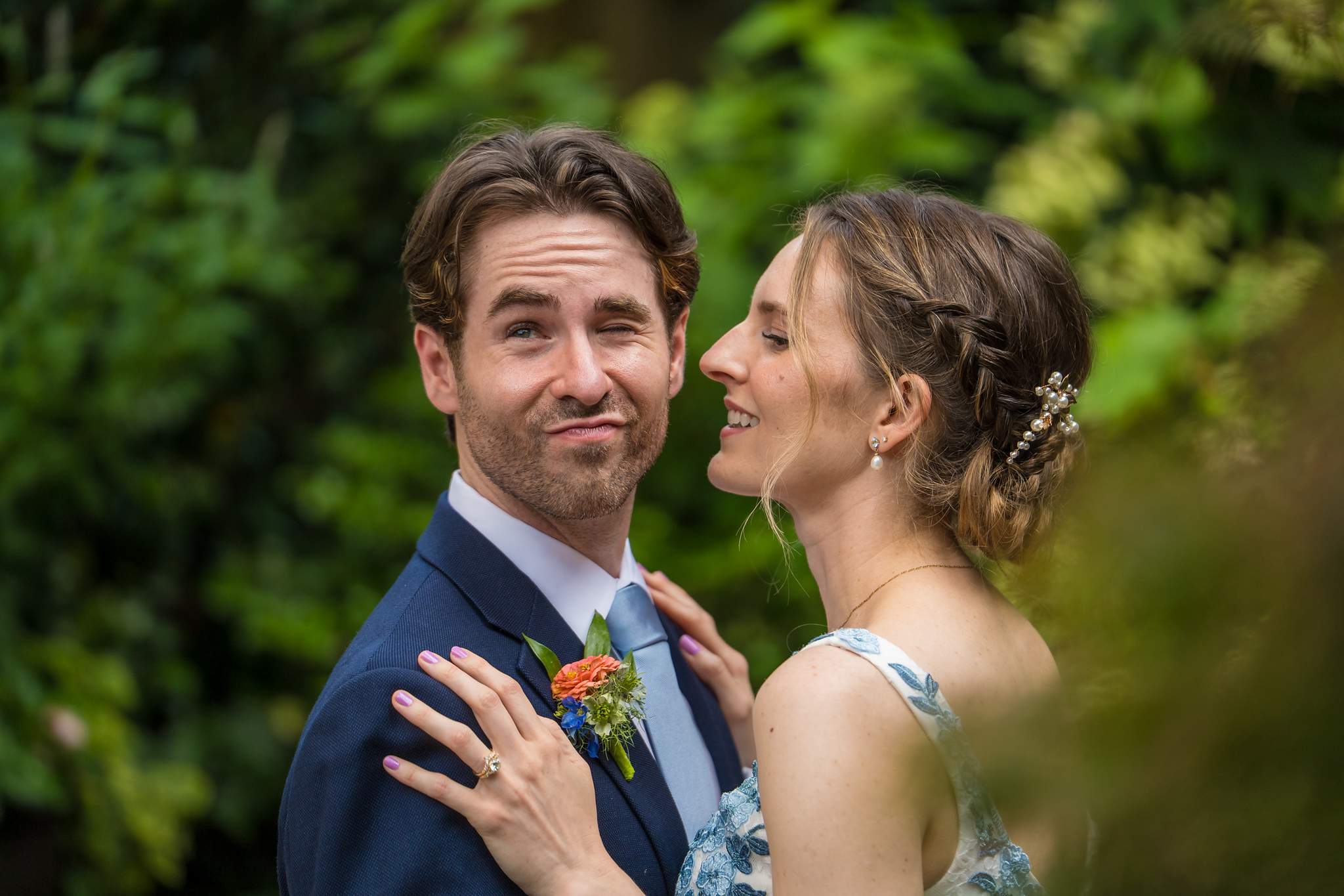 Close portrait of the couple with green garden foliage behind them