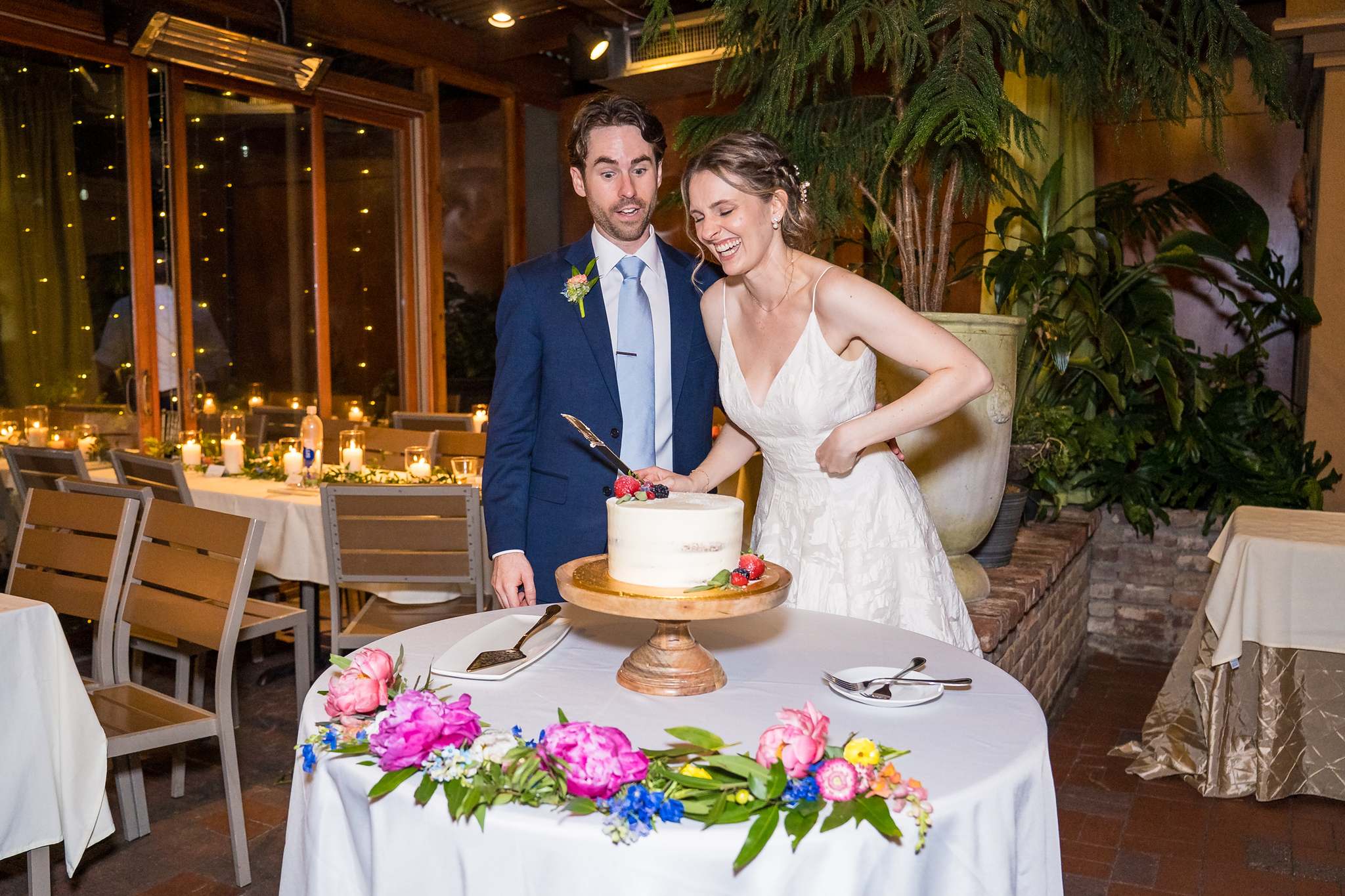 Couple with their wedding cake and bright florals at Wahoo! Grill