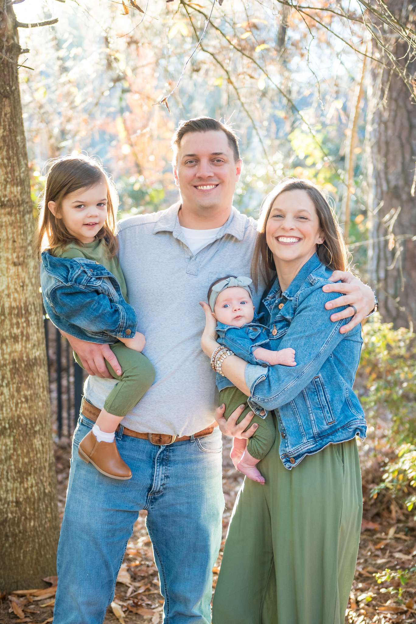 Olive jumpsuit, gray polo, jeans and tiny denim jackets on a family of four among pine trees