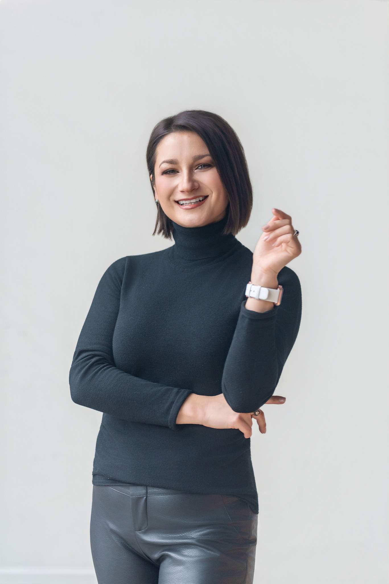 Woman in a fitted black turtleneck against a light gray wall