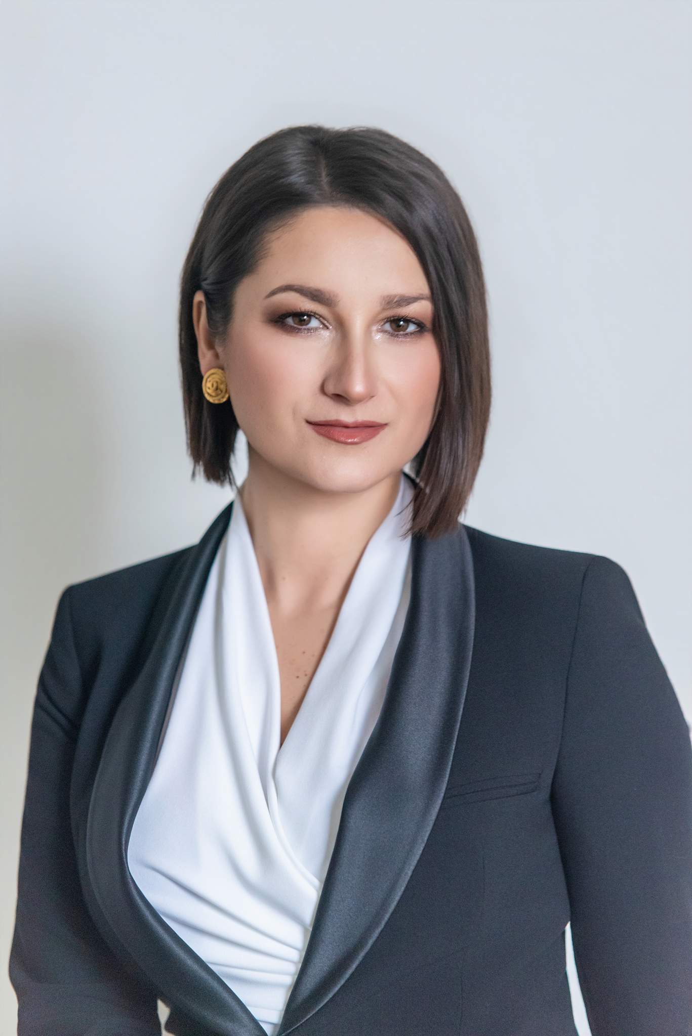 Close headshot of a woman in a black suit jacket and white draped blouse
