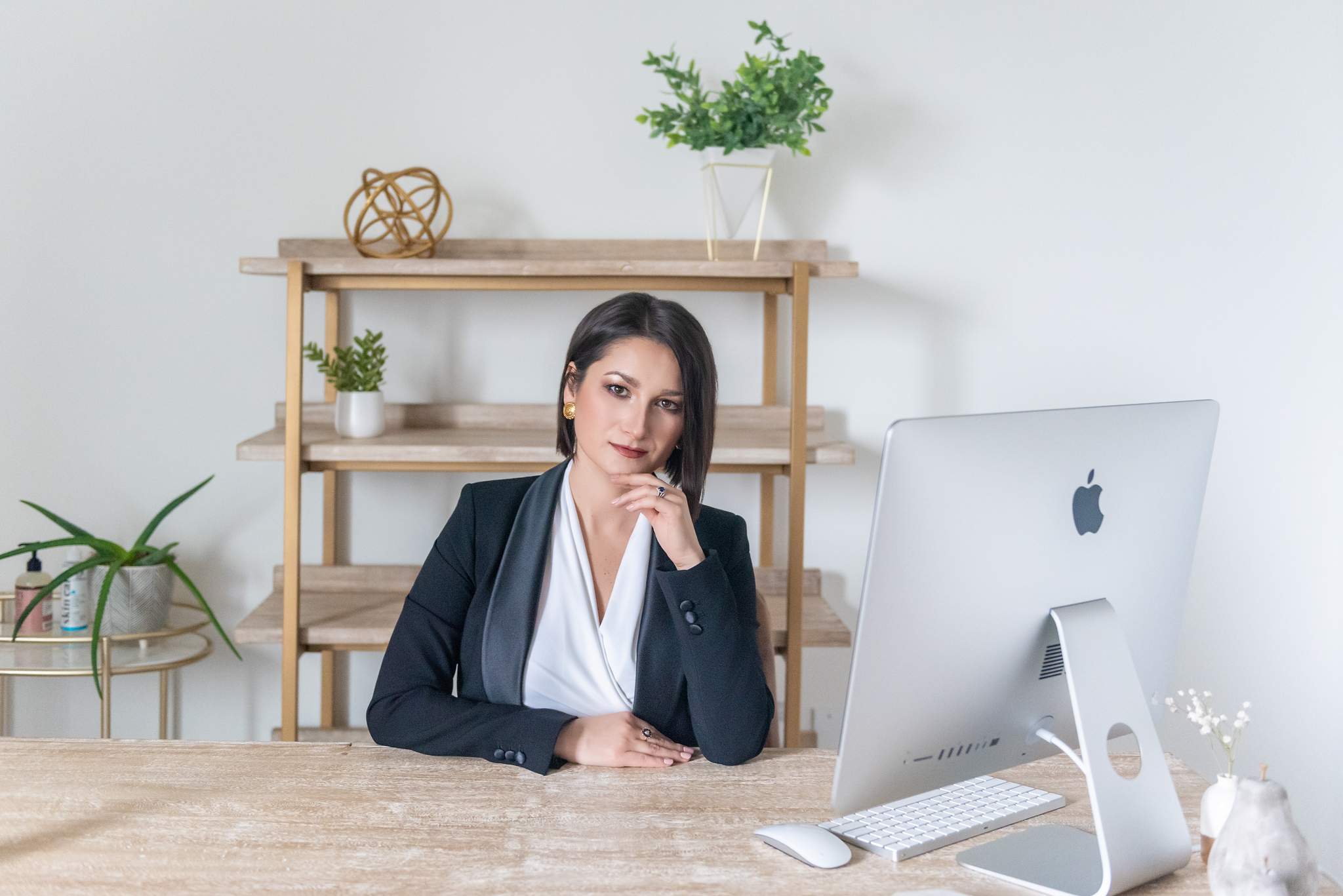 Branding headshot of a woman in a black suit at a desk with a laptop and computer